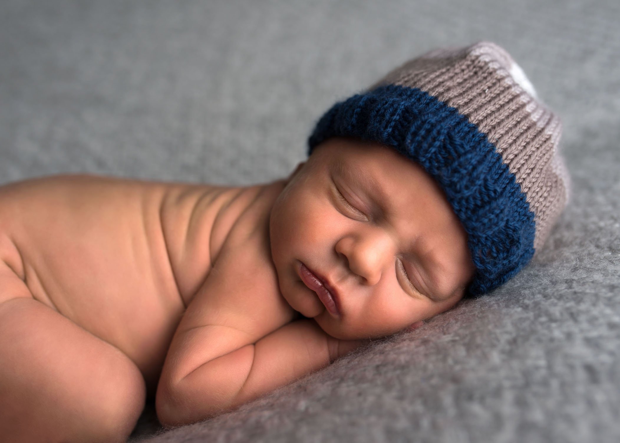 newborn baby sleeping with hat on and a grumpy face One Big Happy Photo