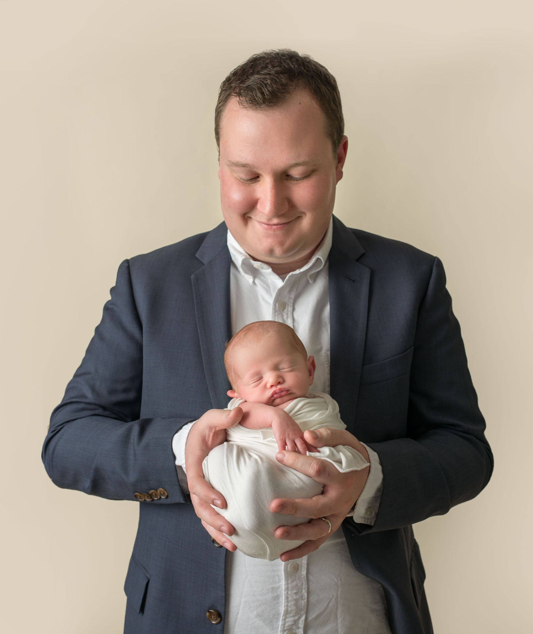 Dad holding newborn son like a ball on his chest One Big Happy Photo