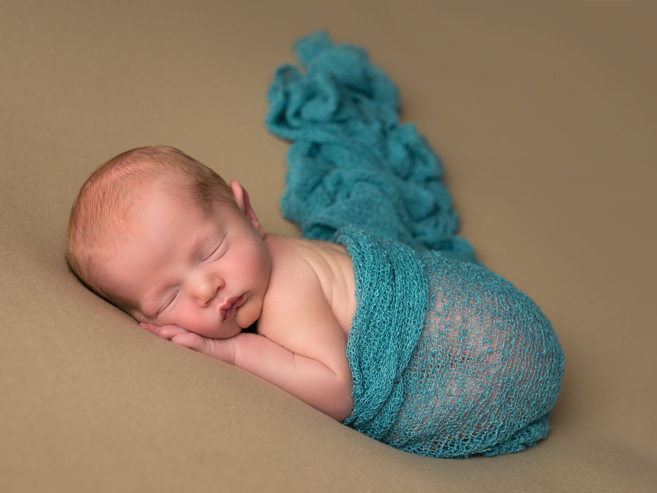newborn baby photo on tan background with aqua wrap One Big Happy Photo