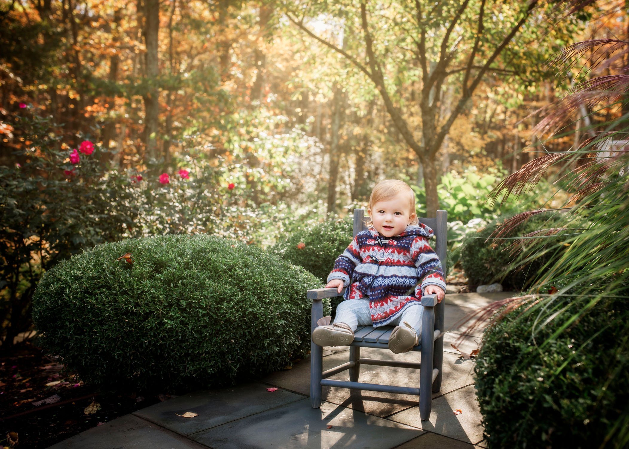 12 month old girl sits in toddler chair outside in fall