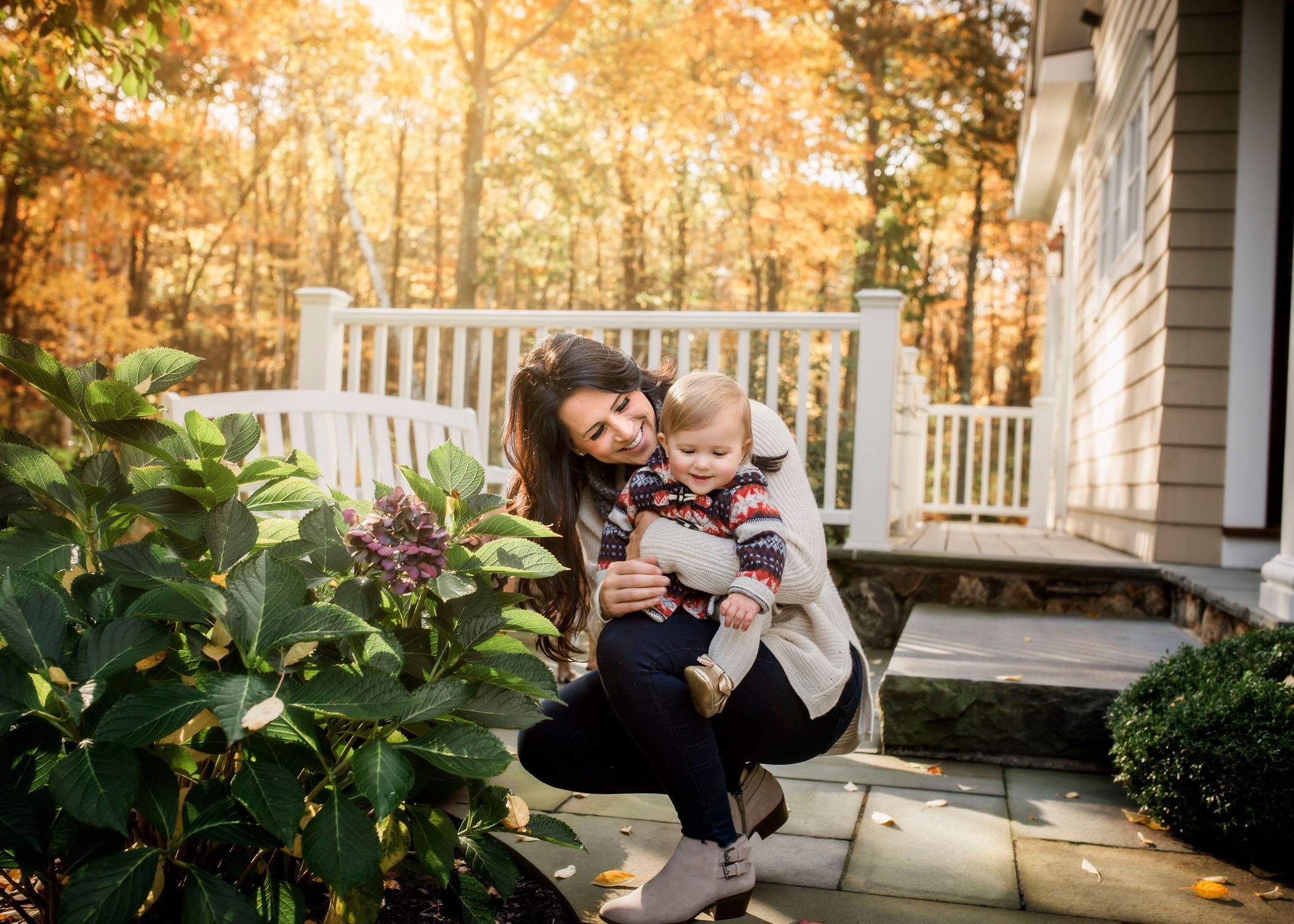Mom and 12 month old girl looking at flowers outside in fall