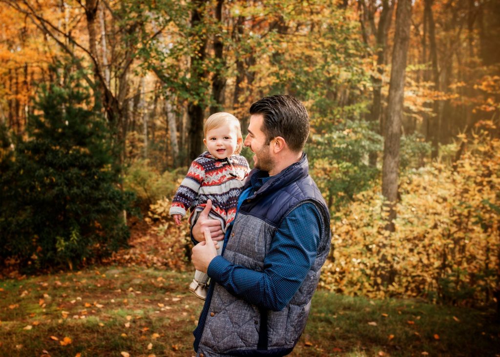 Dad holds 12 month old daughter outside in Fall