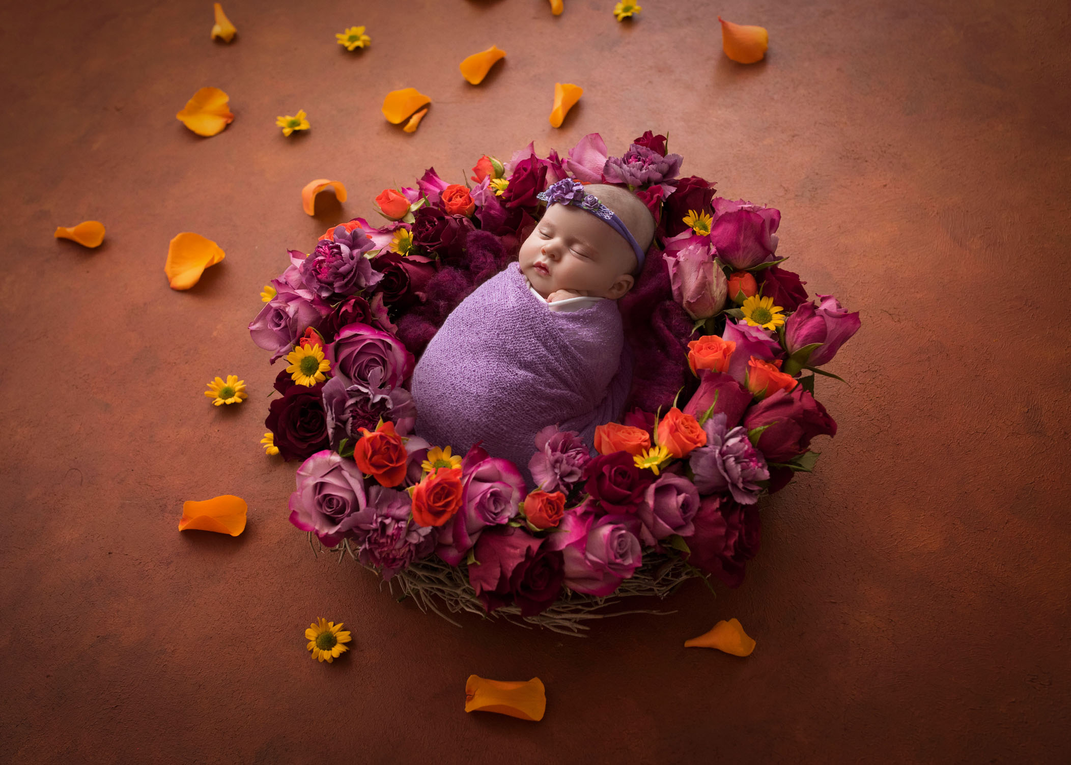 newborn baby girl sleeping in floral nest made of roses