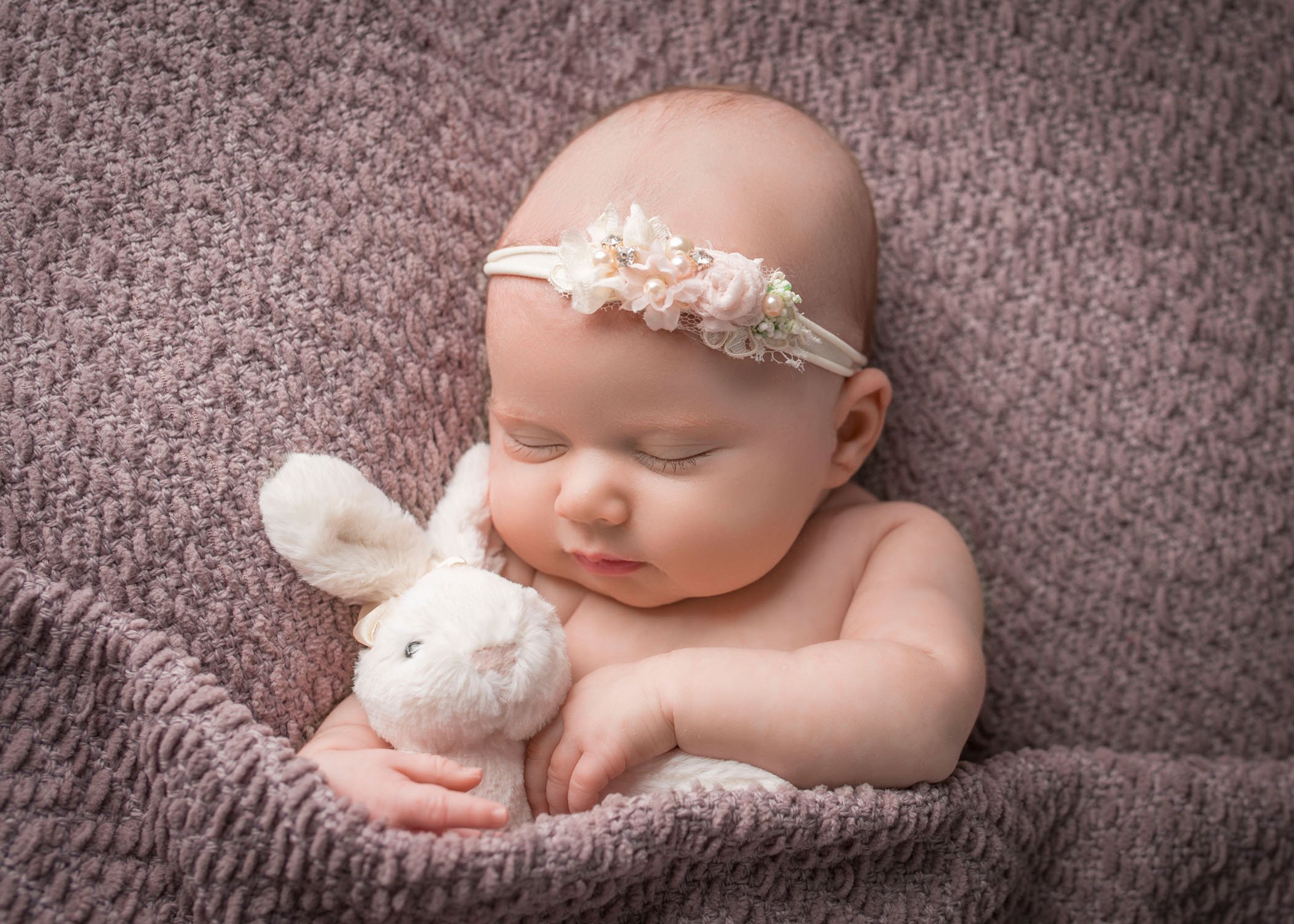 newborn baby girl sleeping with stuffed rabbit
