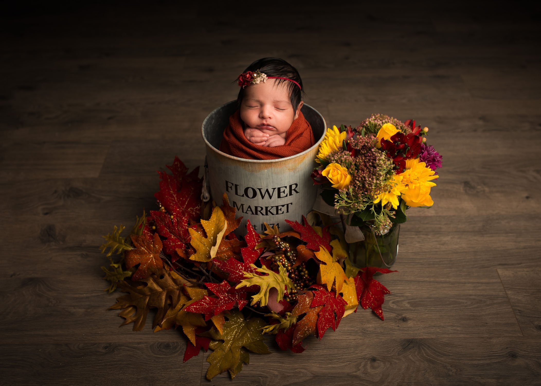 newborn baby sleeping in flower bucket in studio
