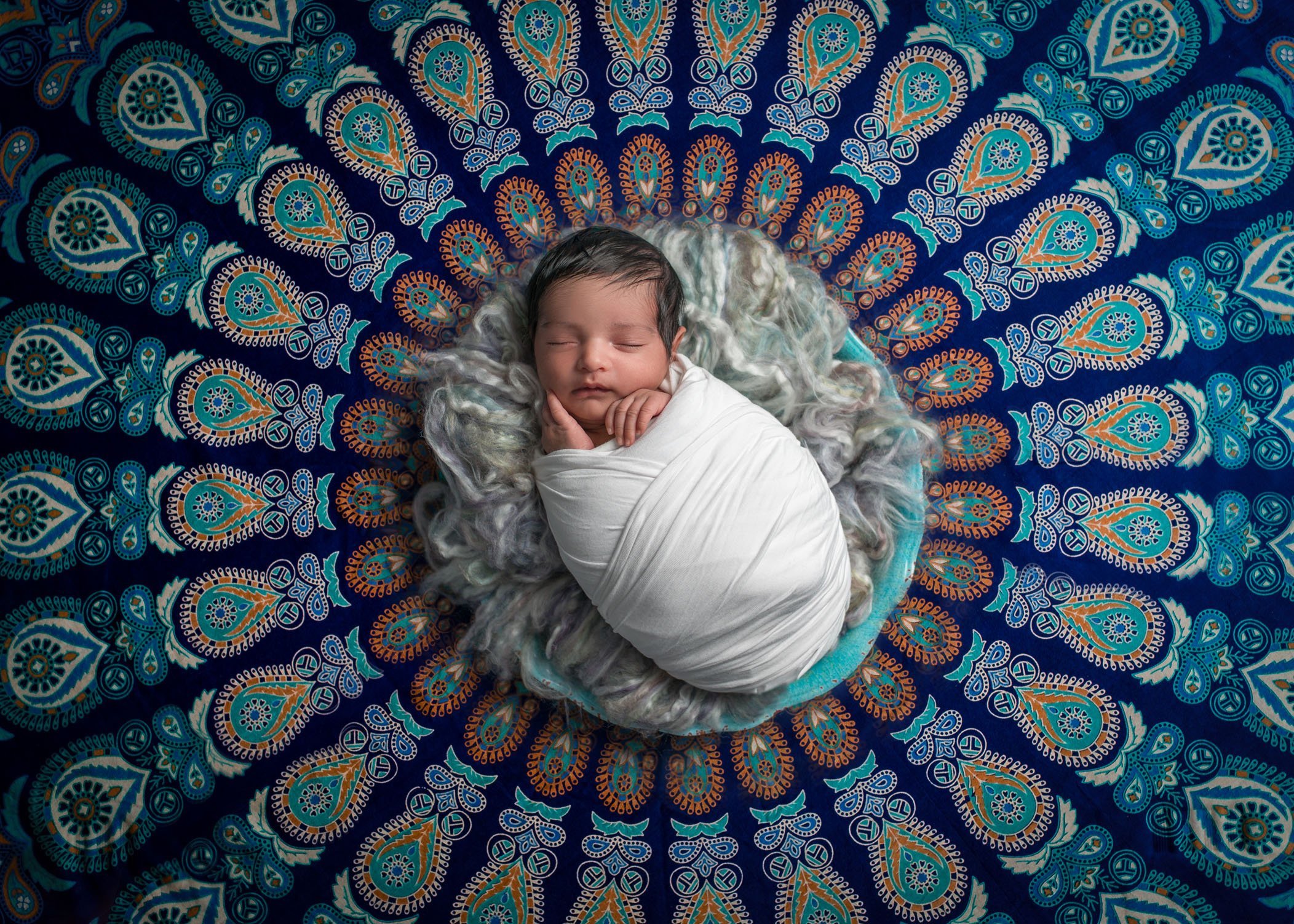 newborn baby sleeping in center of indian spiral tapestry