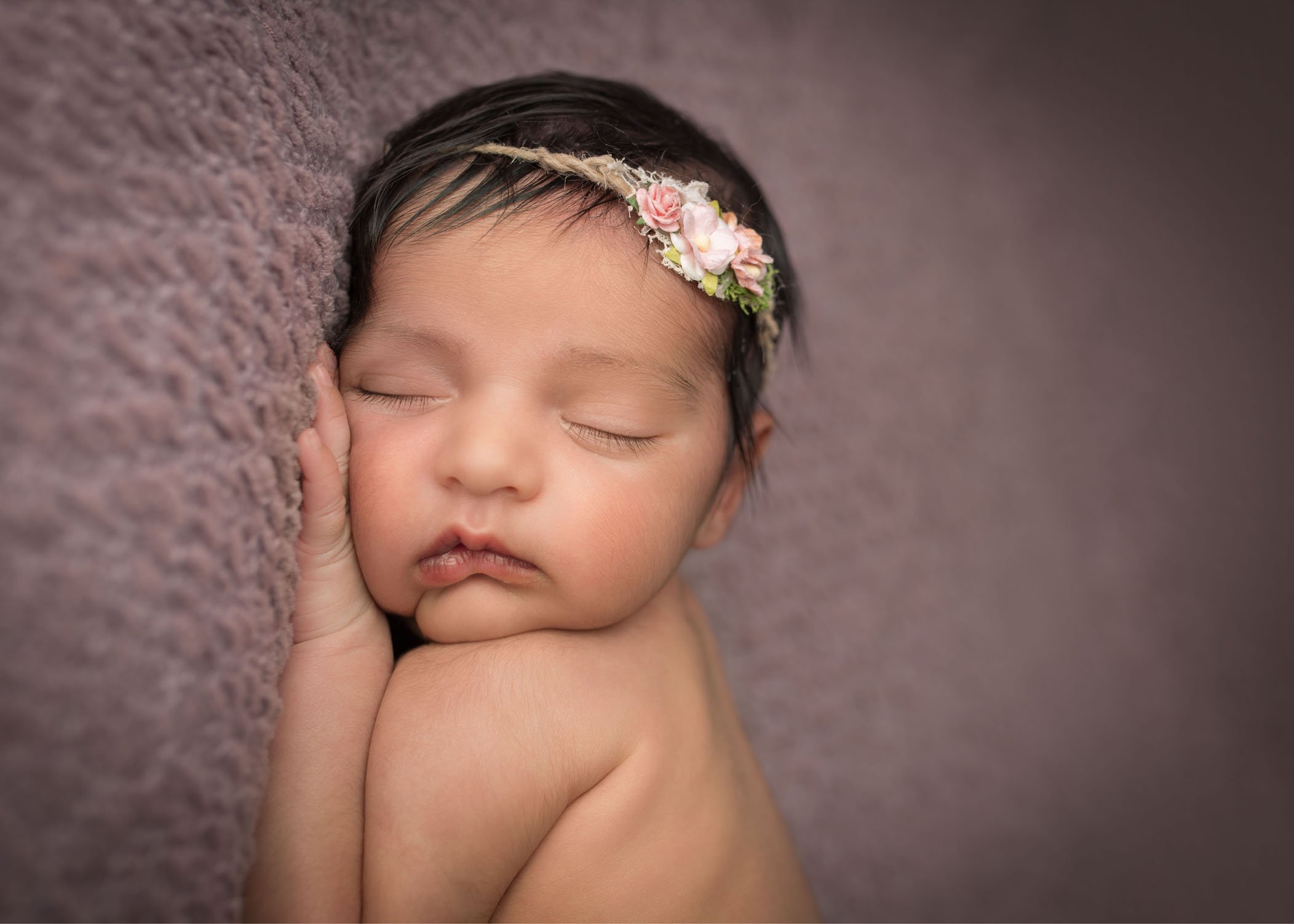 close up of newborn baby girl sleeping on purple