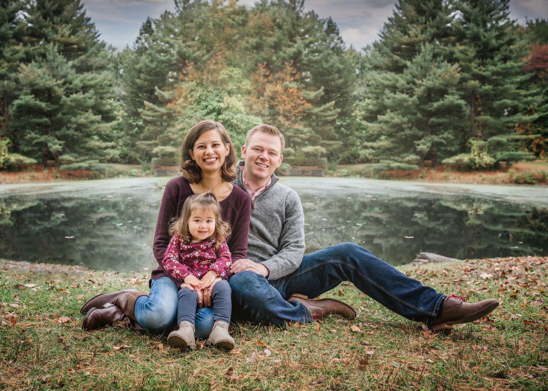 family portrait with 2 year old girl sitting in front of a pond
