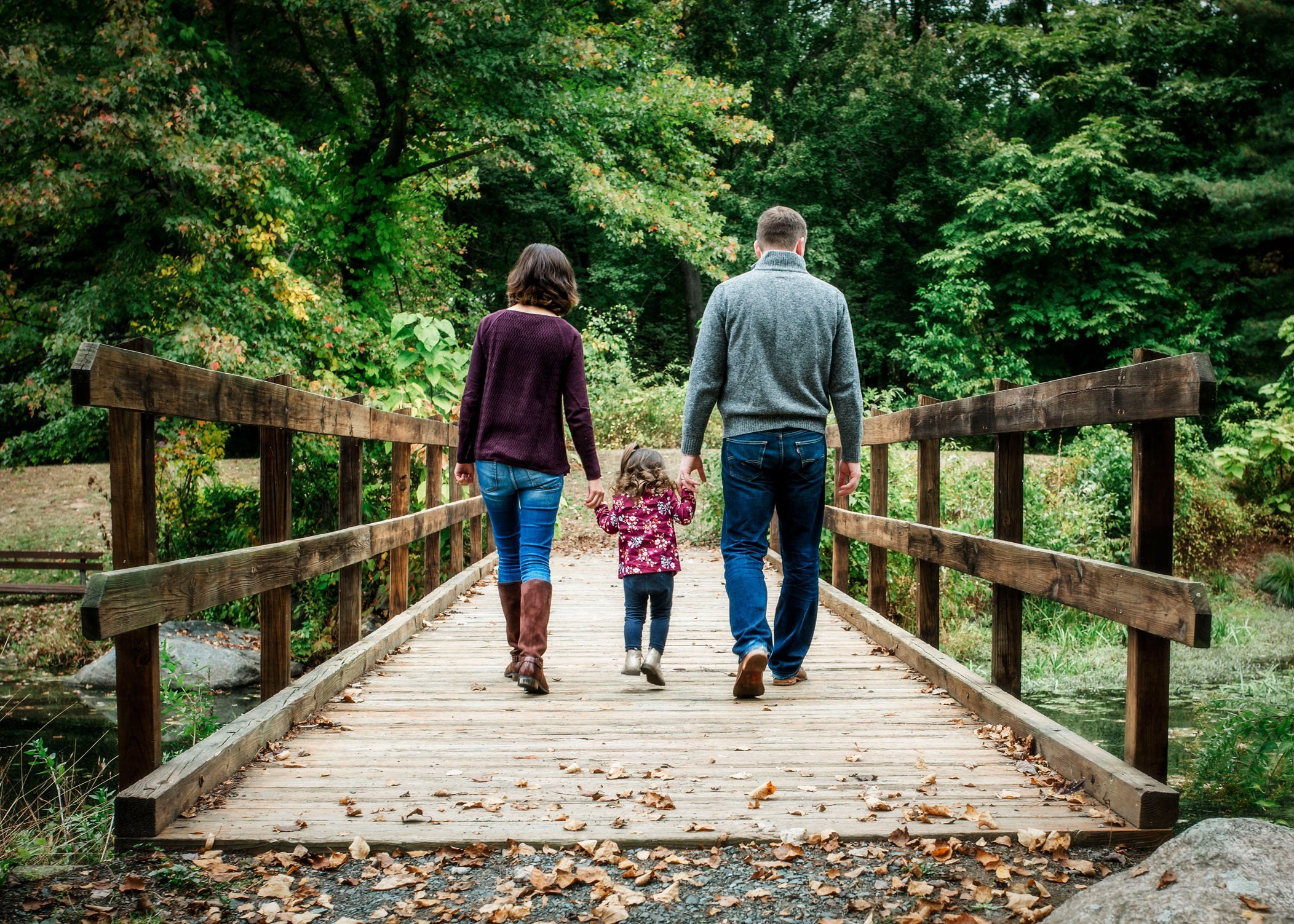 Mom, Dad and 2 year old walking across a bridge