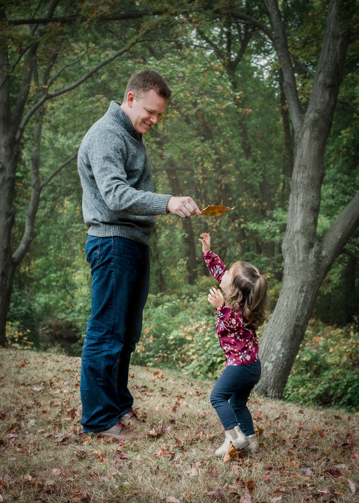 Dad holding big leaf for 2 year old to jump and get