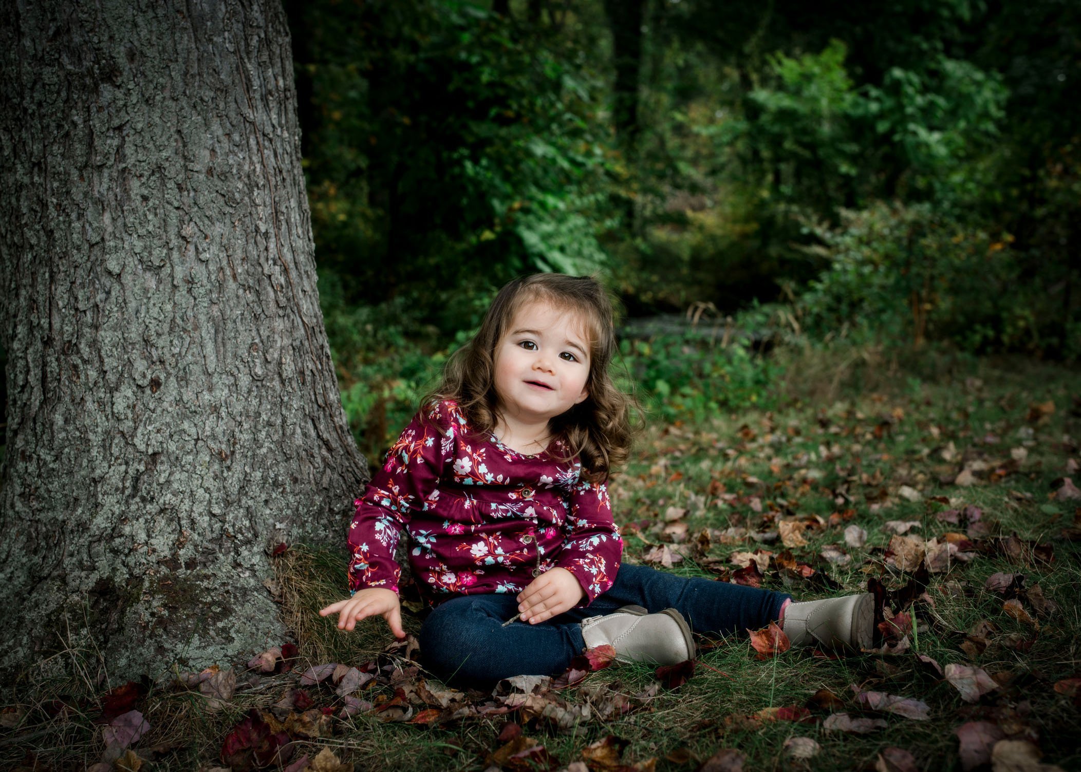 2 year old girl sitting by a tree