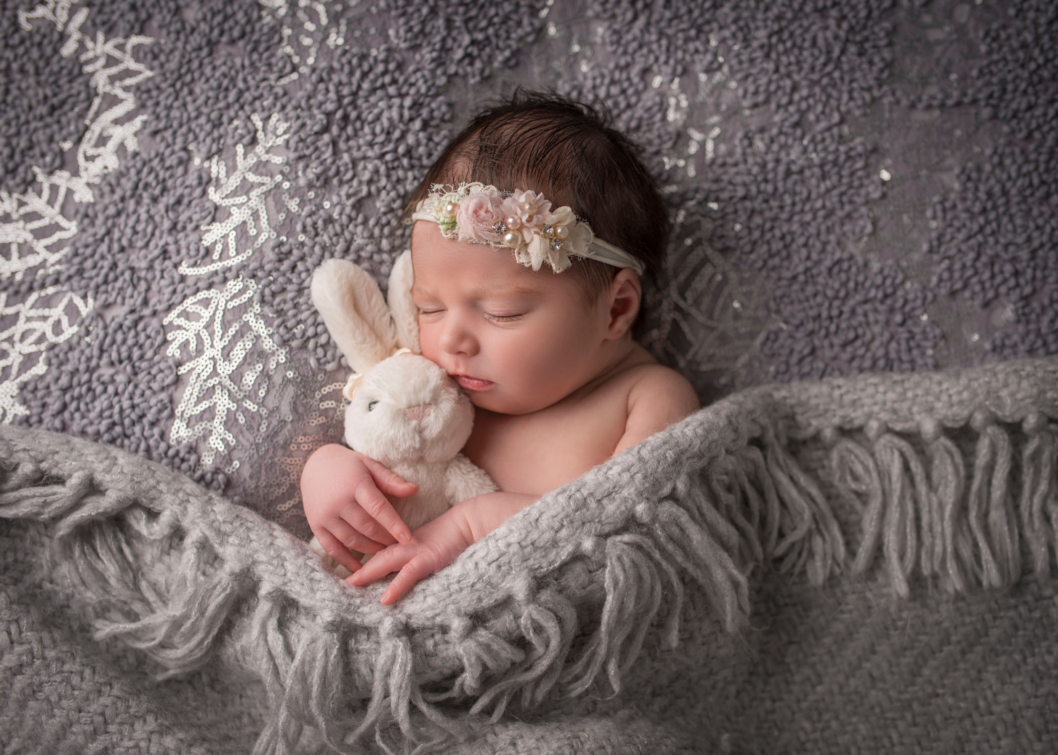 newborn baby girls sleeping with bunny on grey lace background