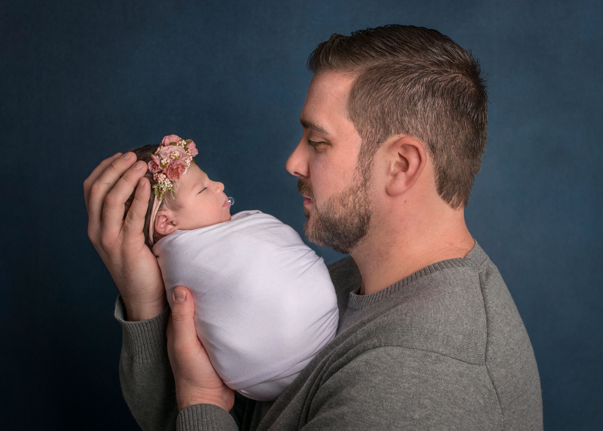 Dad holding newborn baby girl with bubble on her lips