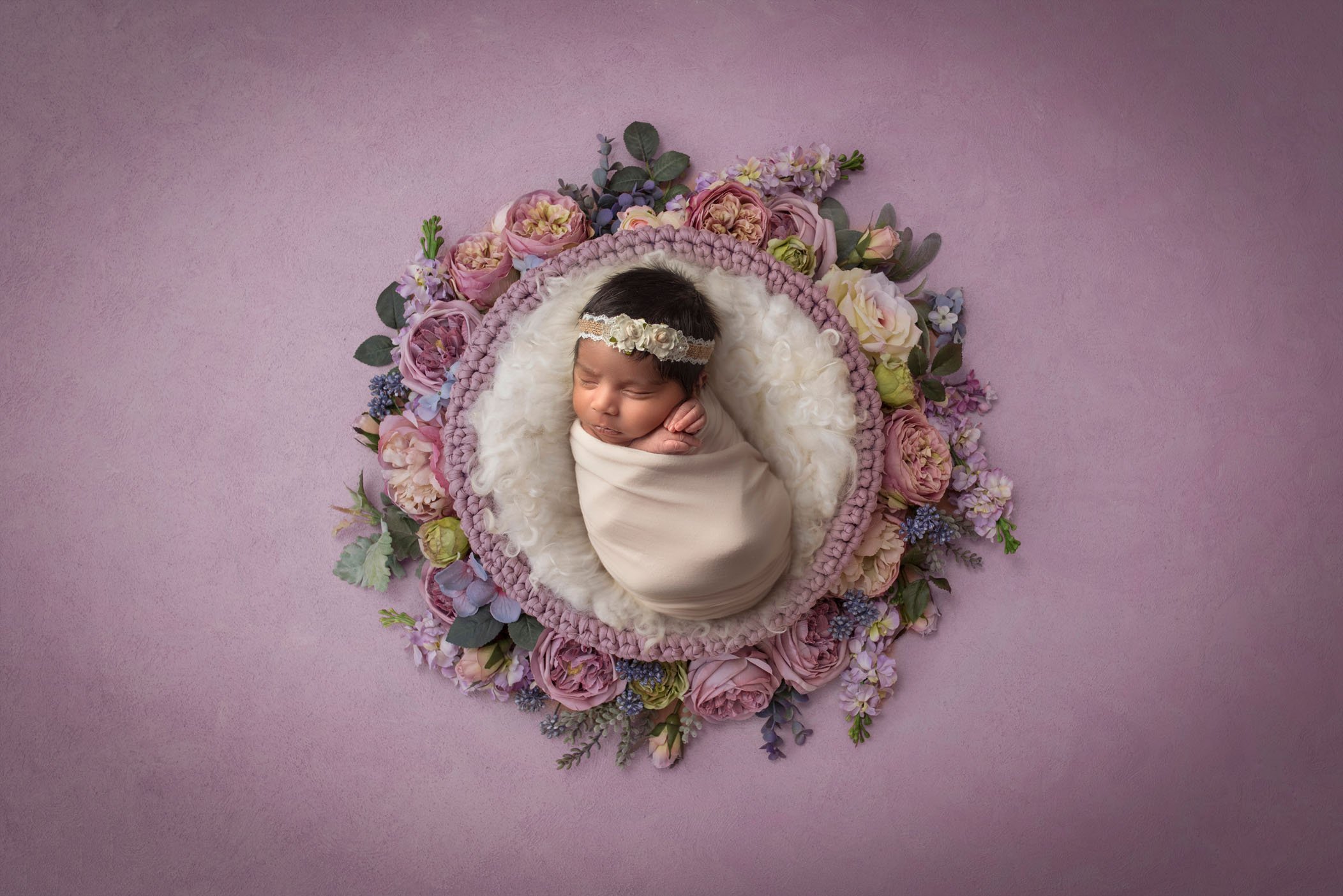 newborn baby girl sleeping in lavender ring of flowers