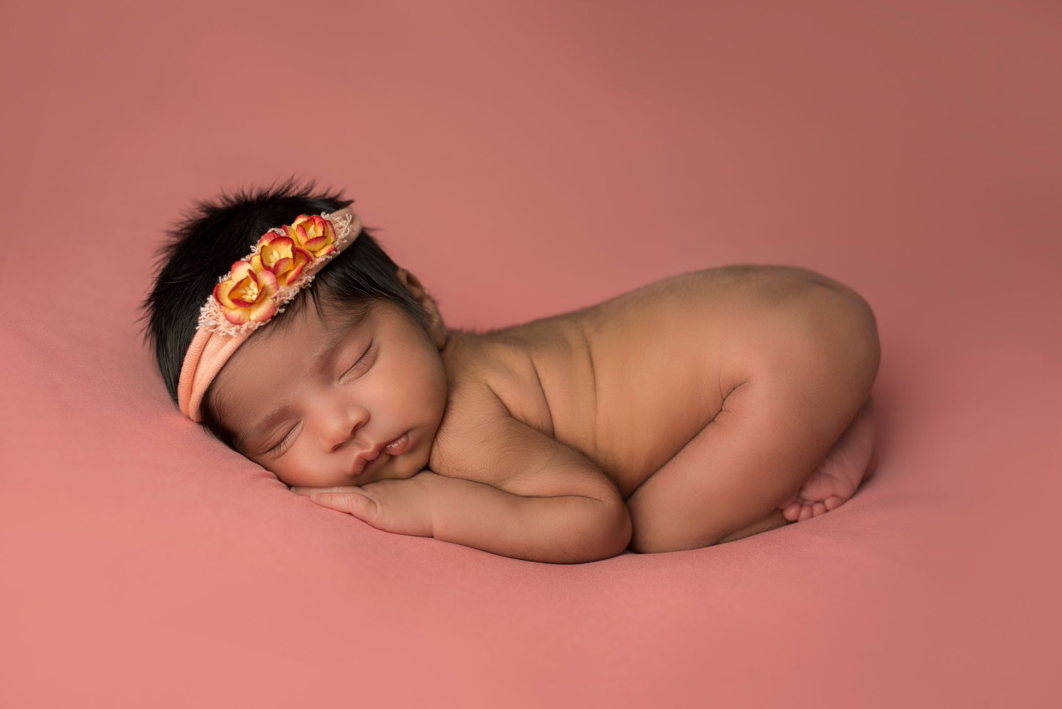 newborn baby girl sleeping in bum up pose on coral colored background