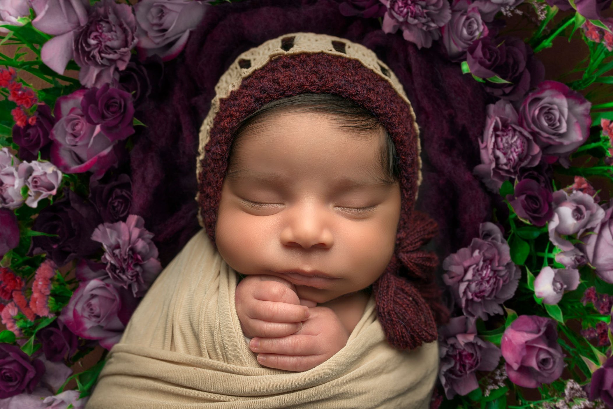 close up of newborn sleeping in purple flowers