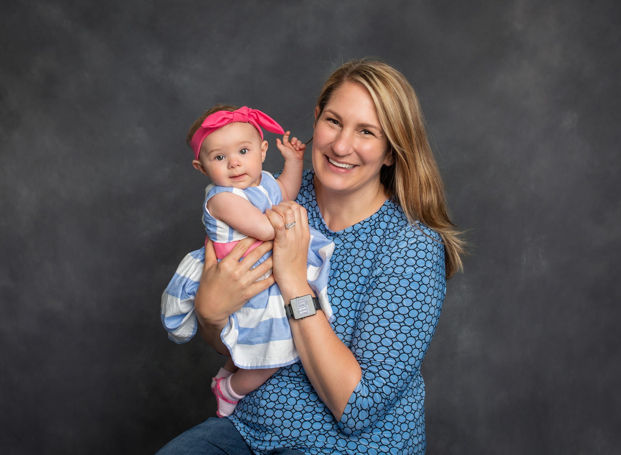 Mom holding her 6 month old baby girl smiling for studio portrait