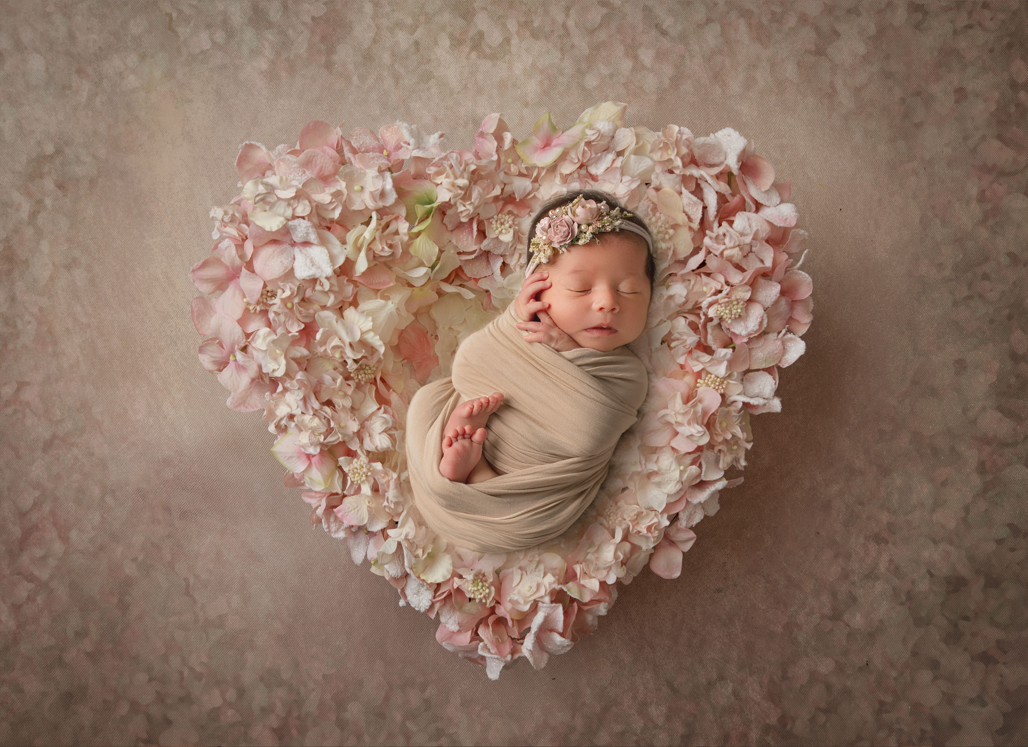 newborn baby girl sleeping in a floral heart prop