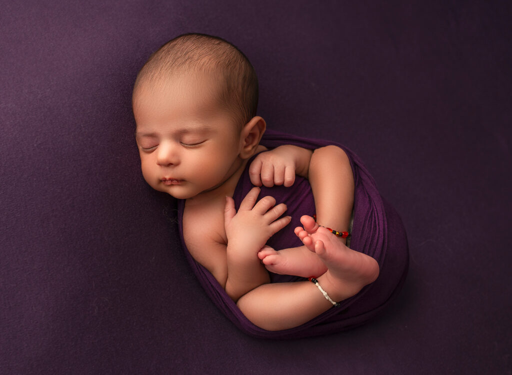 best time to do newborn photos baby boy sleeping on purple blanket