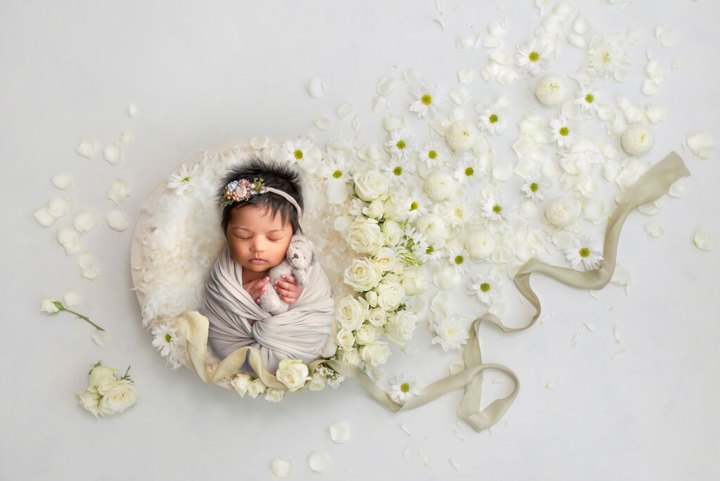 best time for newborn photoshoot baby girl sleeping around white flowers