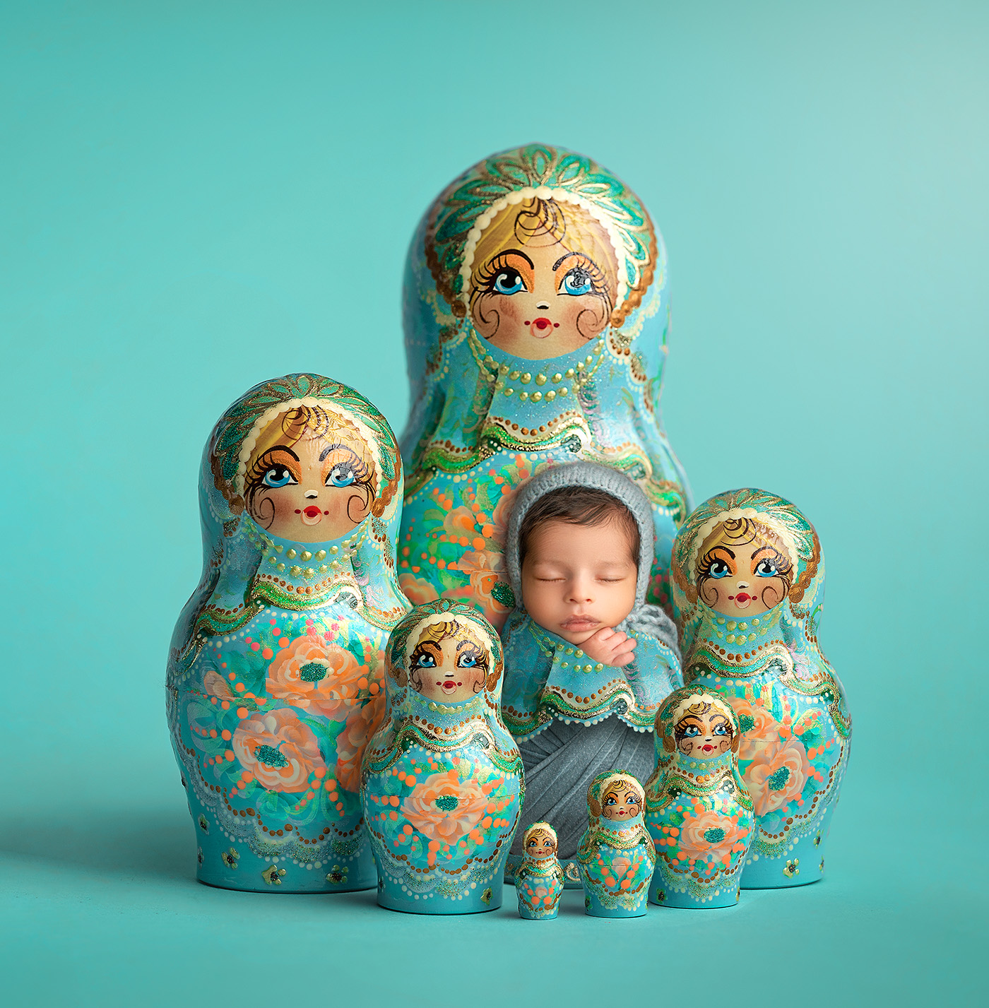 Newborn dressed as Russian doll surrounded by Russian dolls.