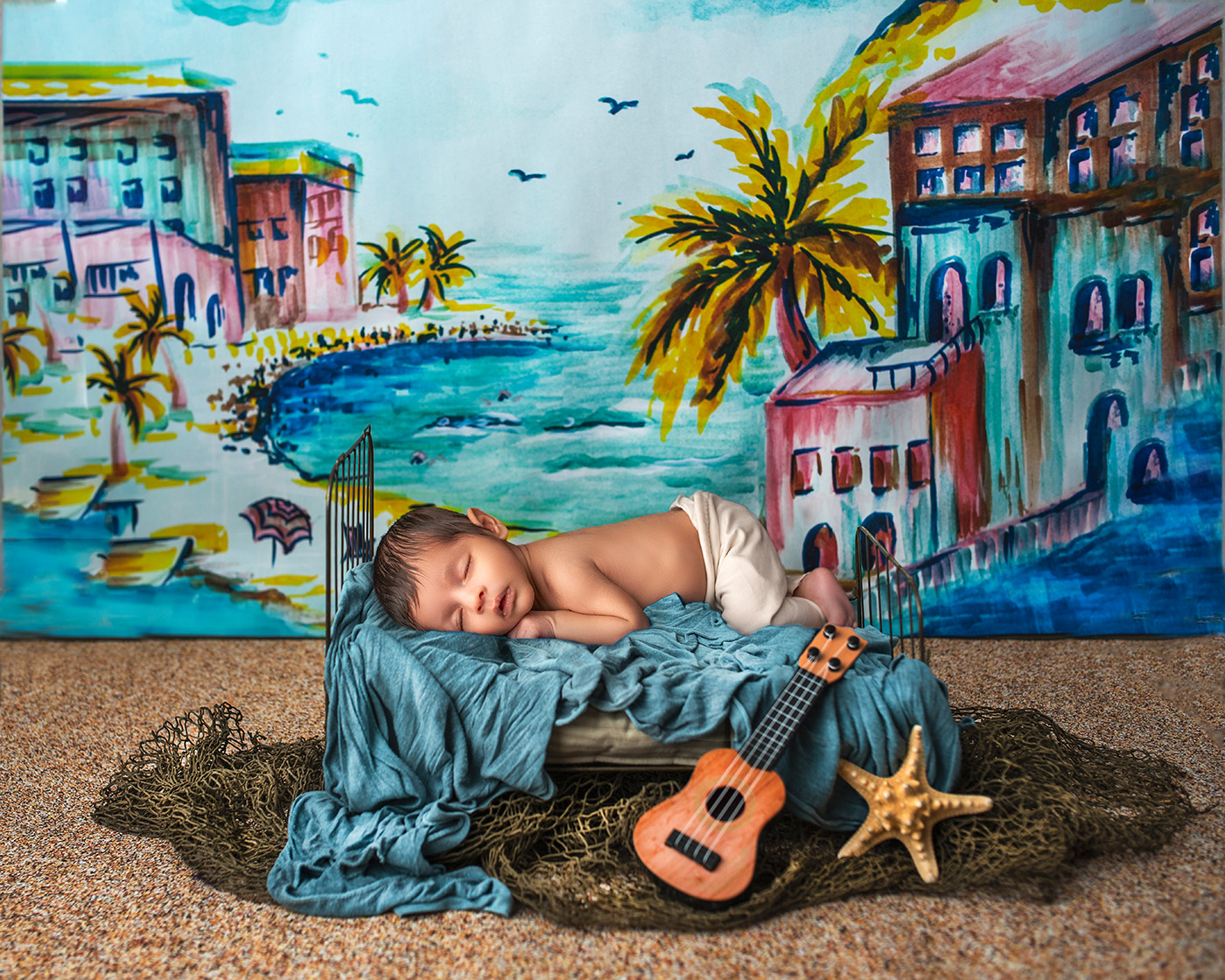 Newborn resting on cot against watercolor beach town backdrop.