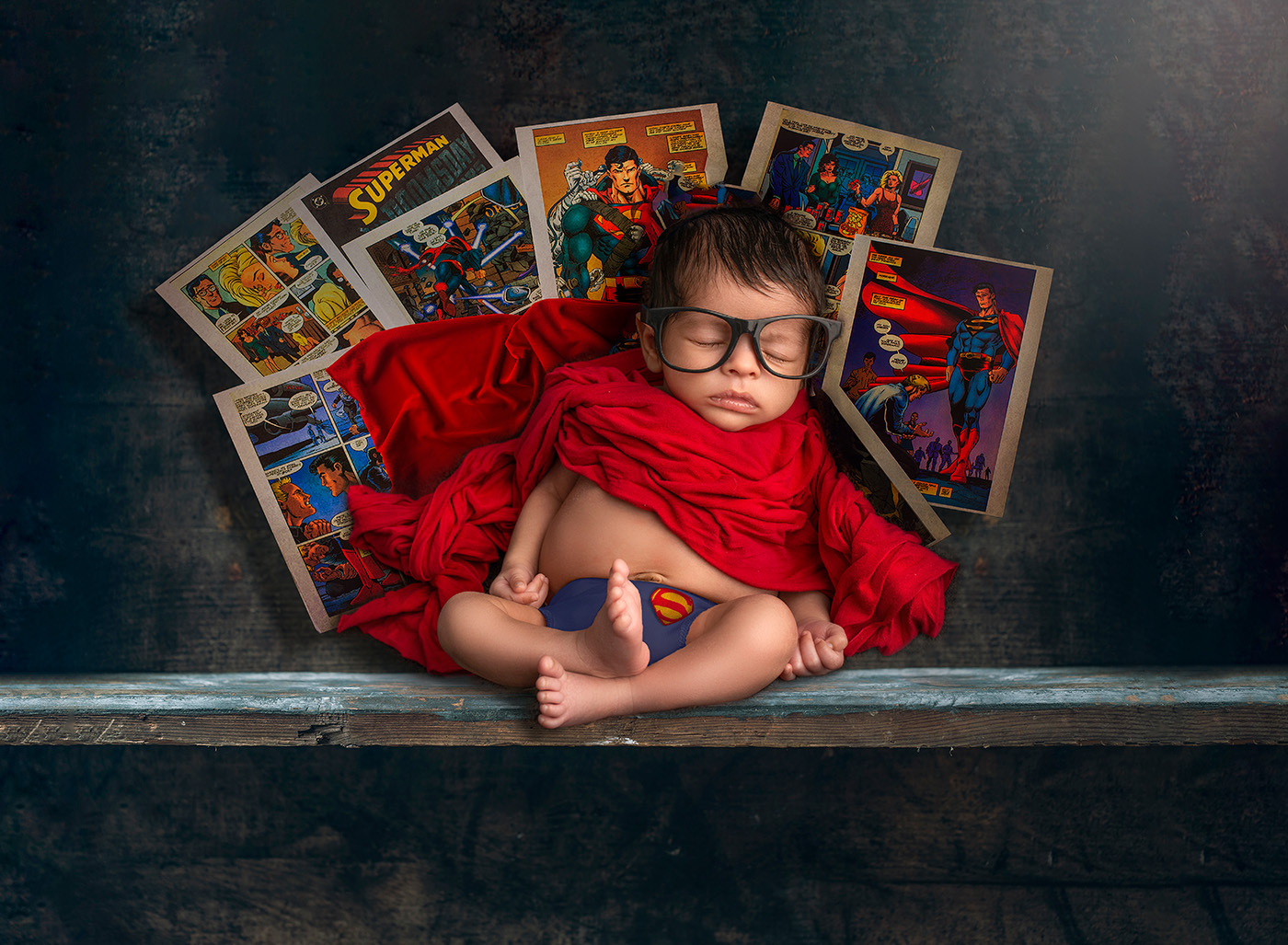 Newborn dressed as Superman taking a nap.