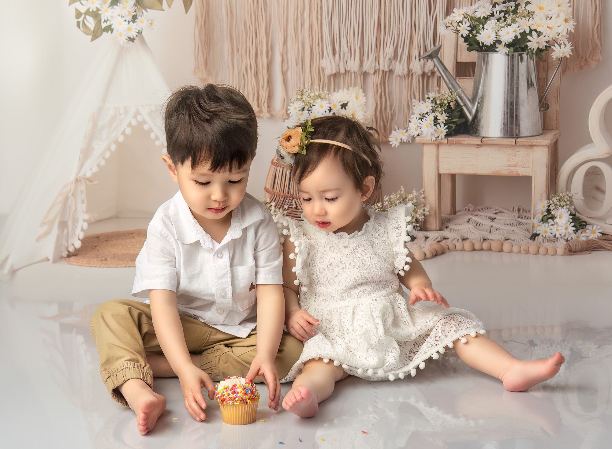 Sophie examining a birthday cupcake while Joshua reaches for it