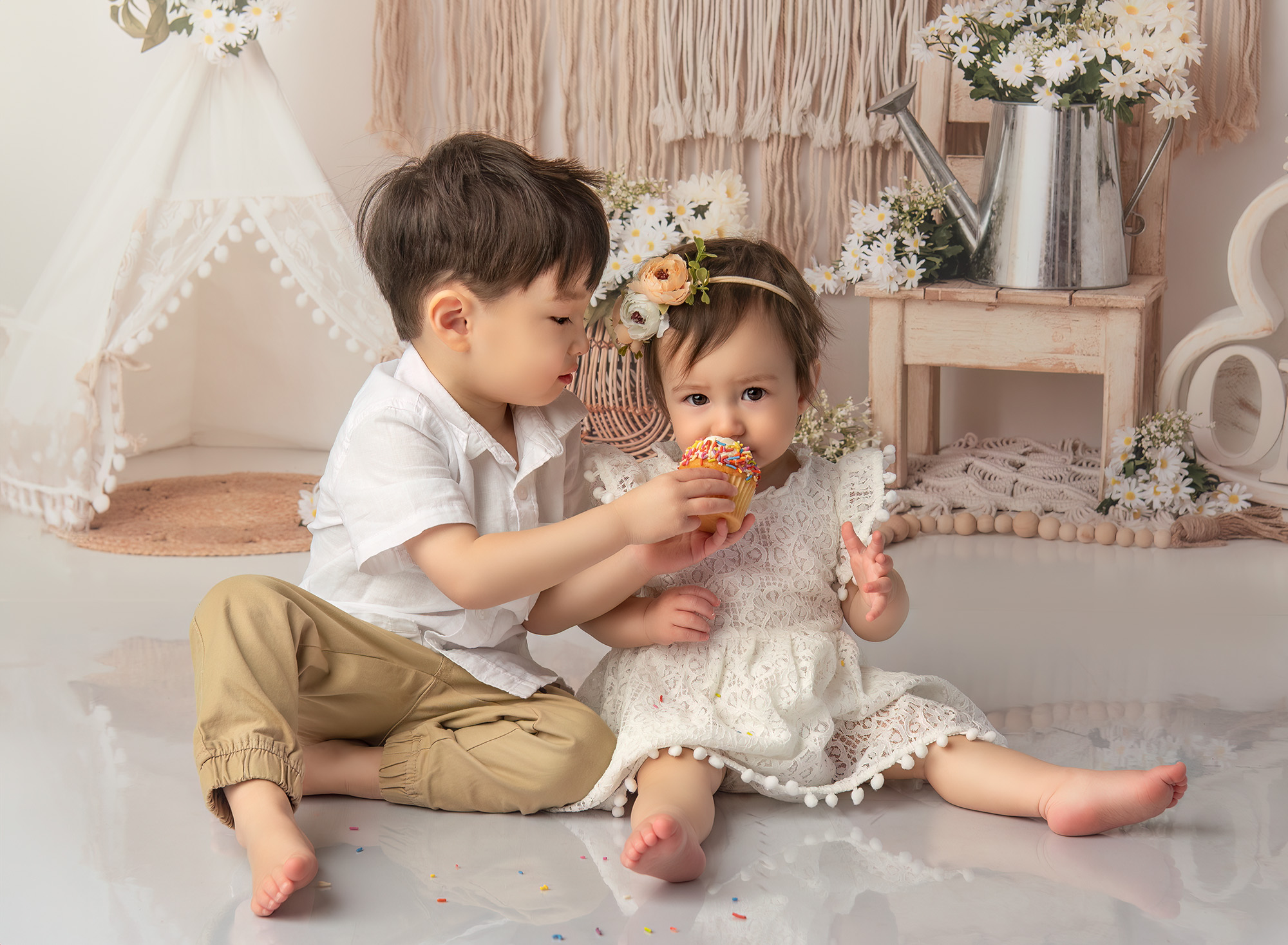 Boho 1 Year Old Photos Joshua lifting the cupcake to Sophie’s mouth to taste the frosting