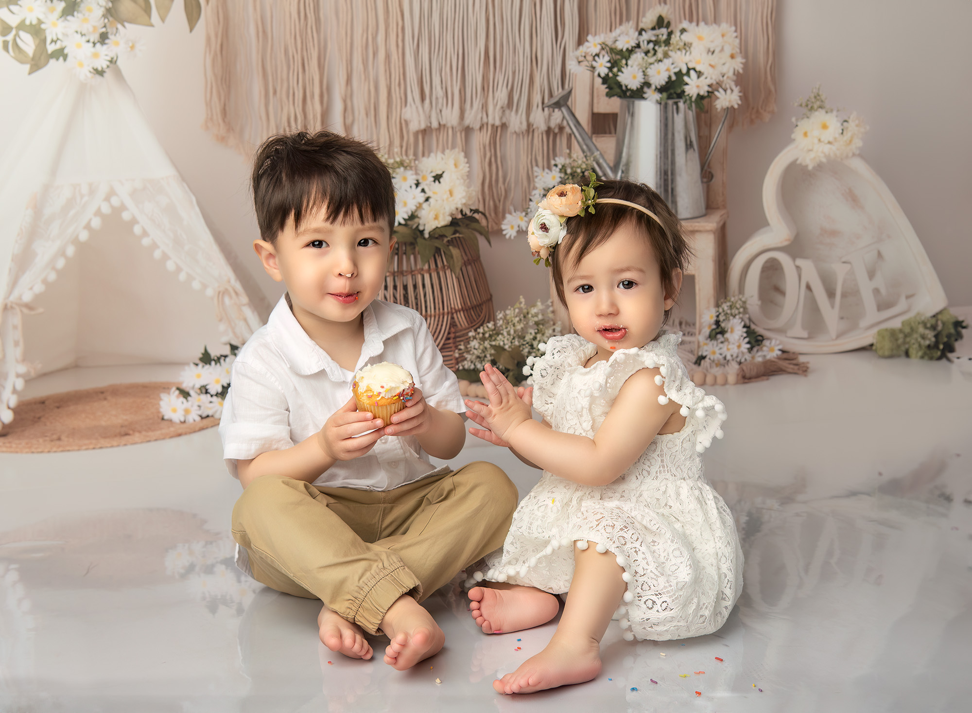 Boho 1 Year Old Photos Sophie and Joshua with frosting on their faces, enjoying the cupcake