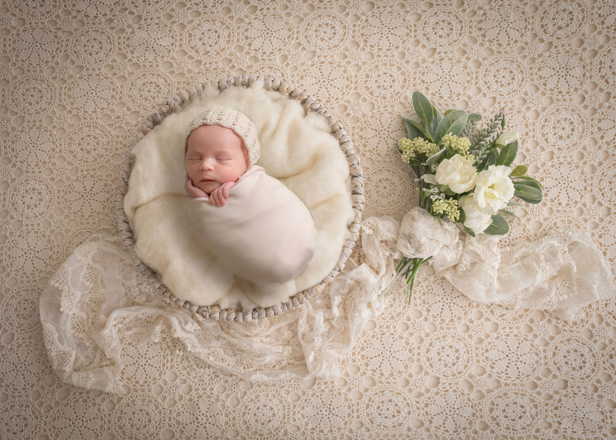 newborn baby girl sleeping in fluff basket on lace background