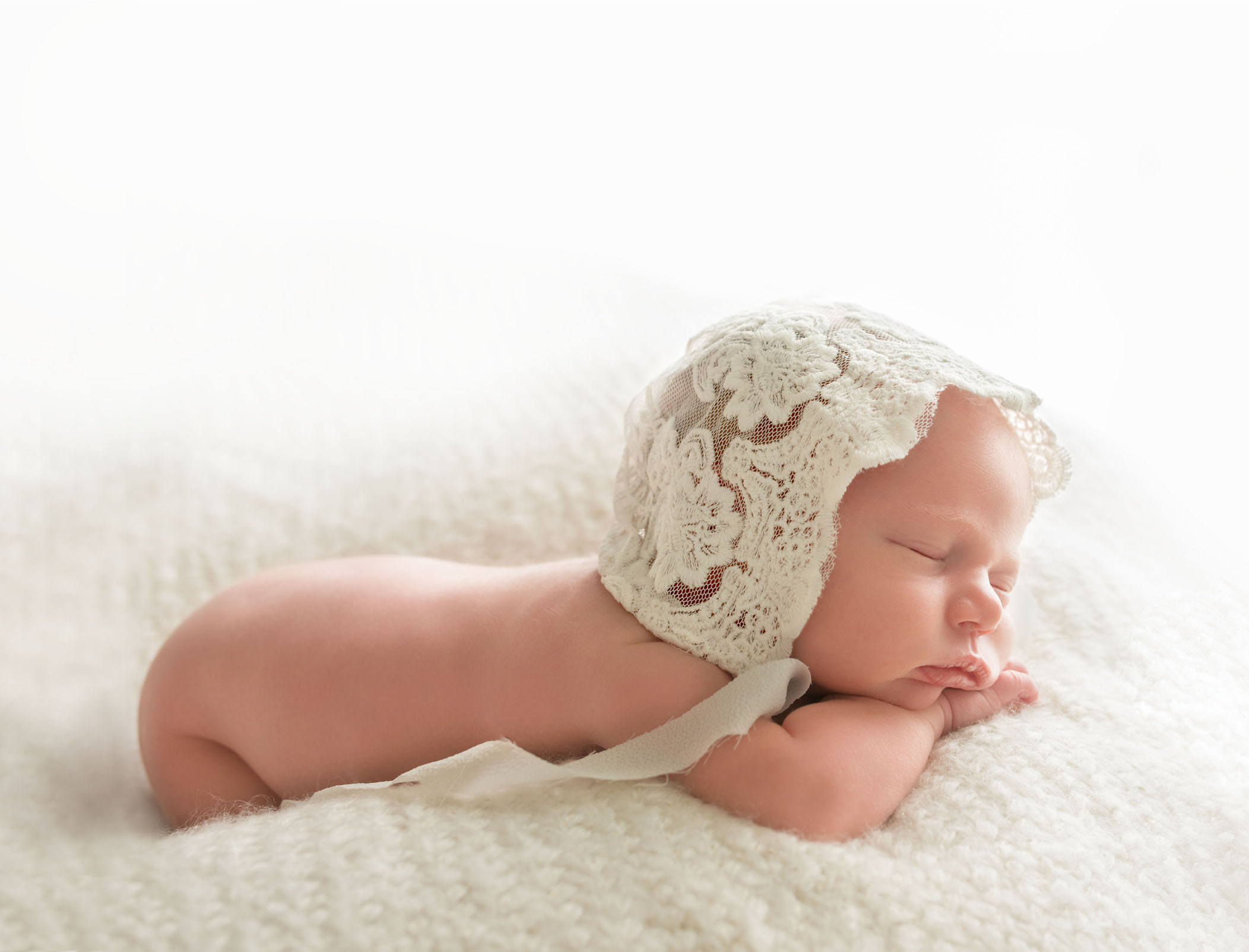newborn baby girl wearing a antique lace bonnet backlit