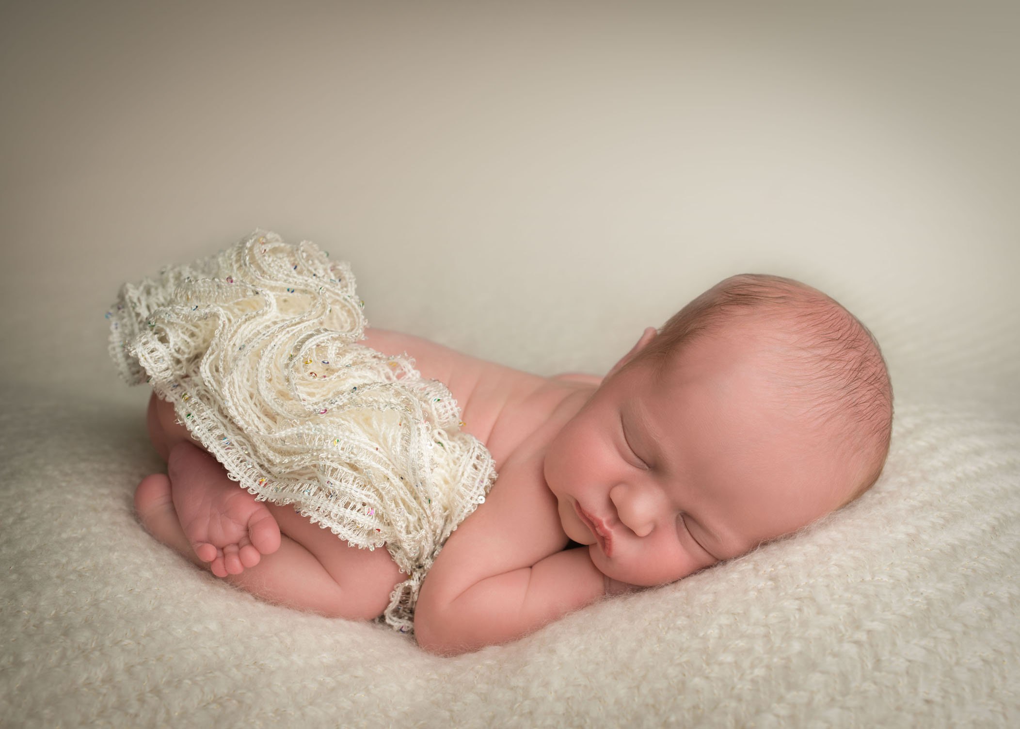newborn baby girl sleeping on cream blanket wearing a tutu