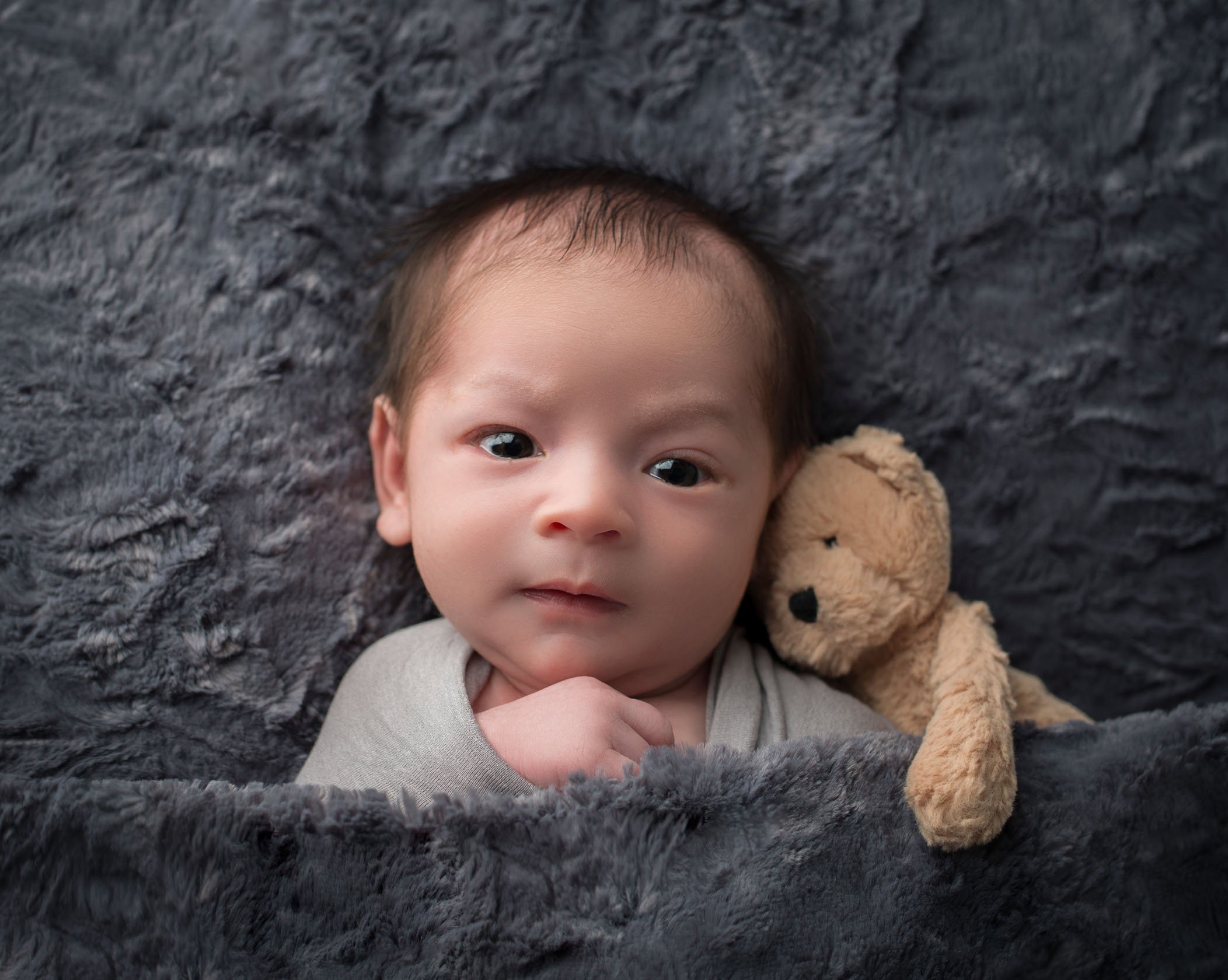 newborn baby boy awake with teddy bear