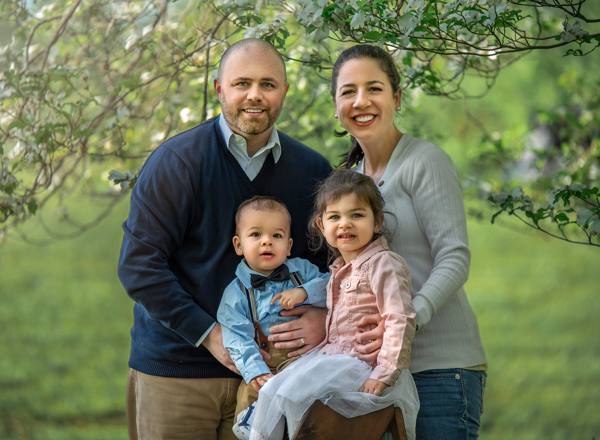 CT Family Photographer smiling couple posing outside with their young daughter and infant son