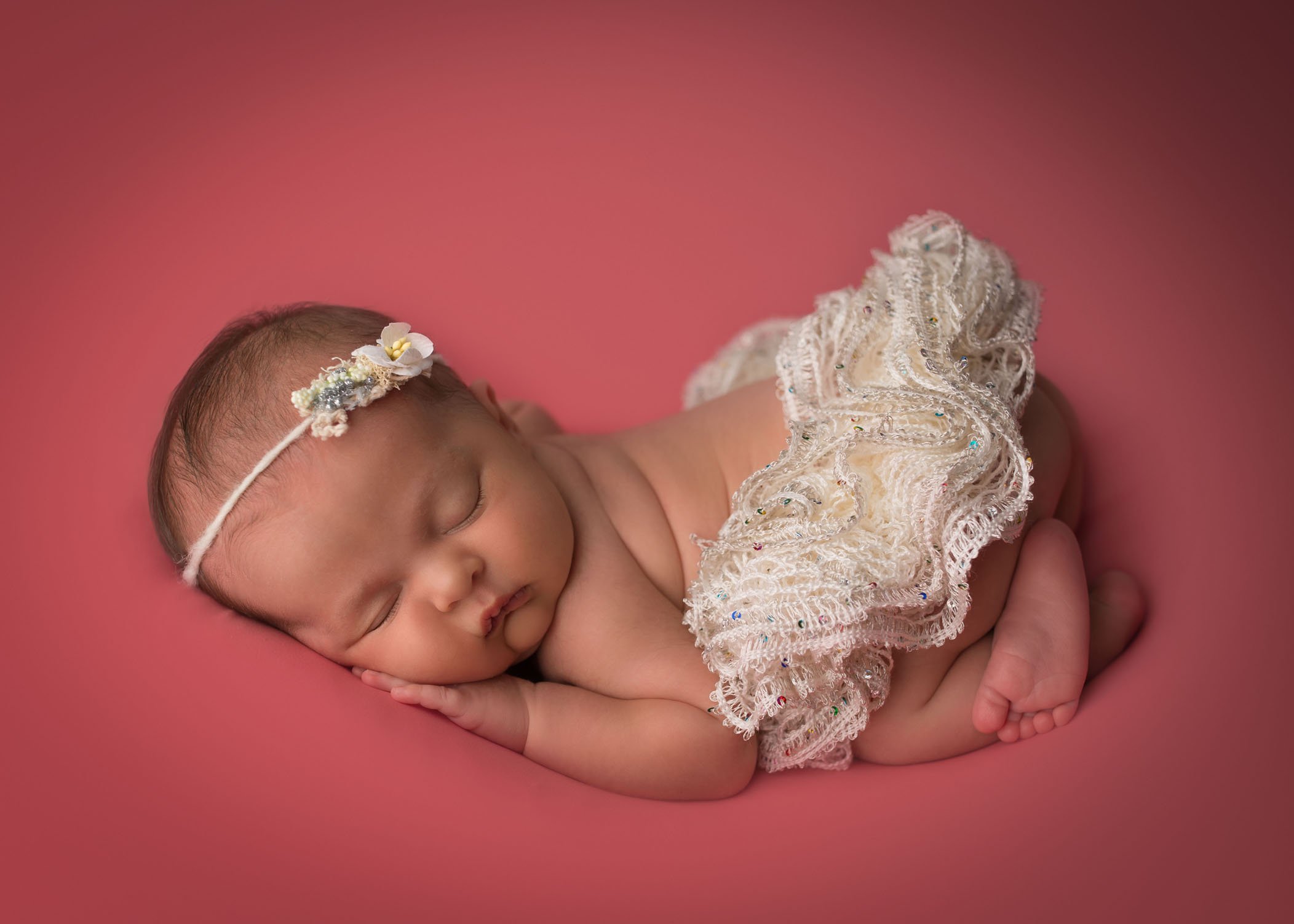 newborn baby ballerina asleep on deep coral blanket