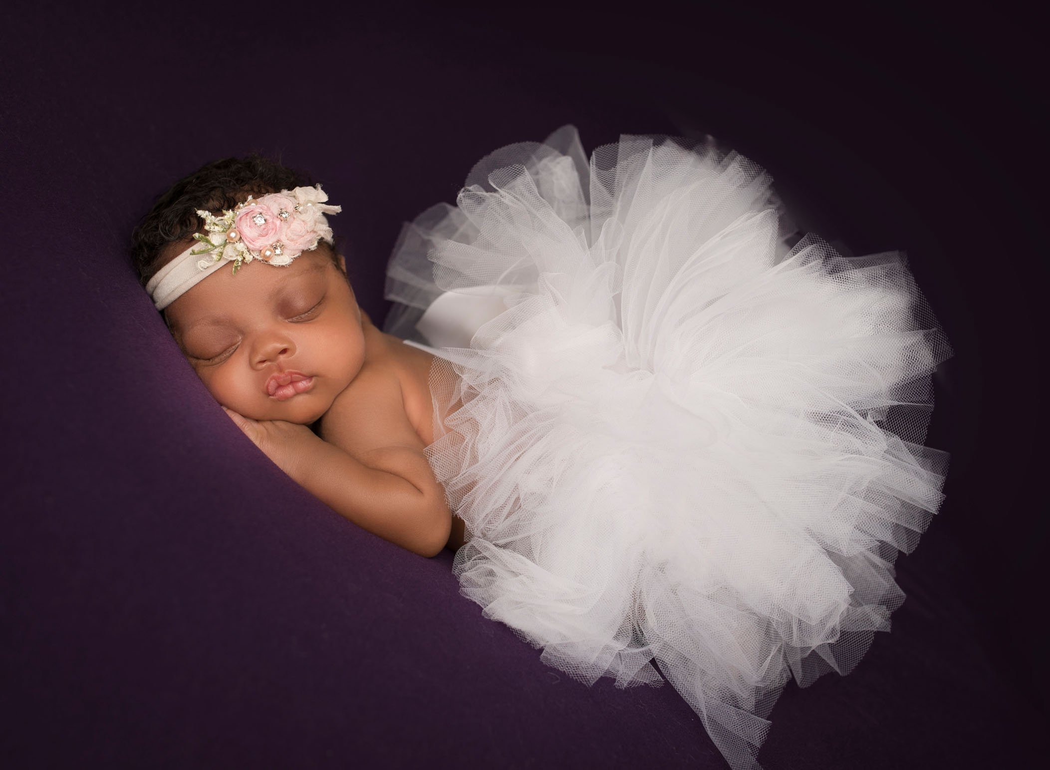 african-american newborn baby girl sleeping in white puffy tutu