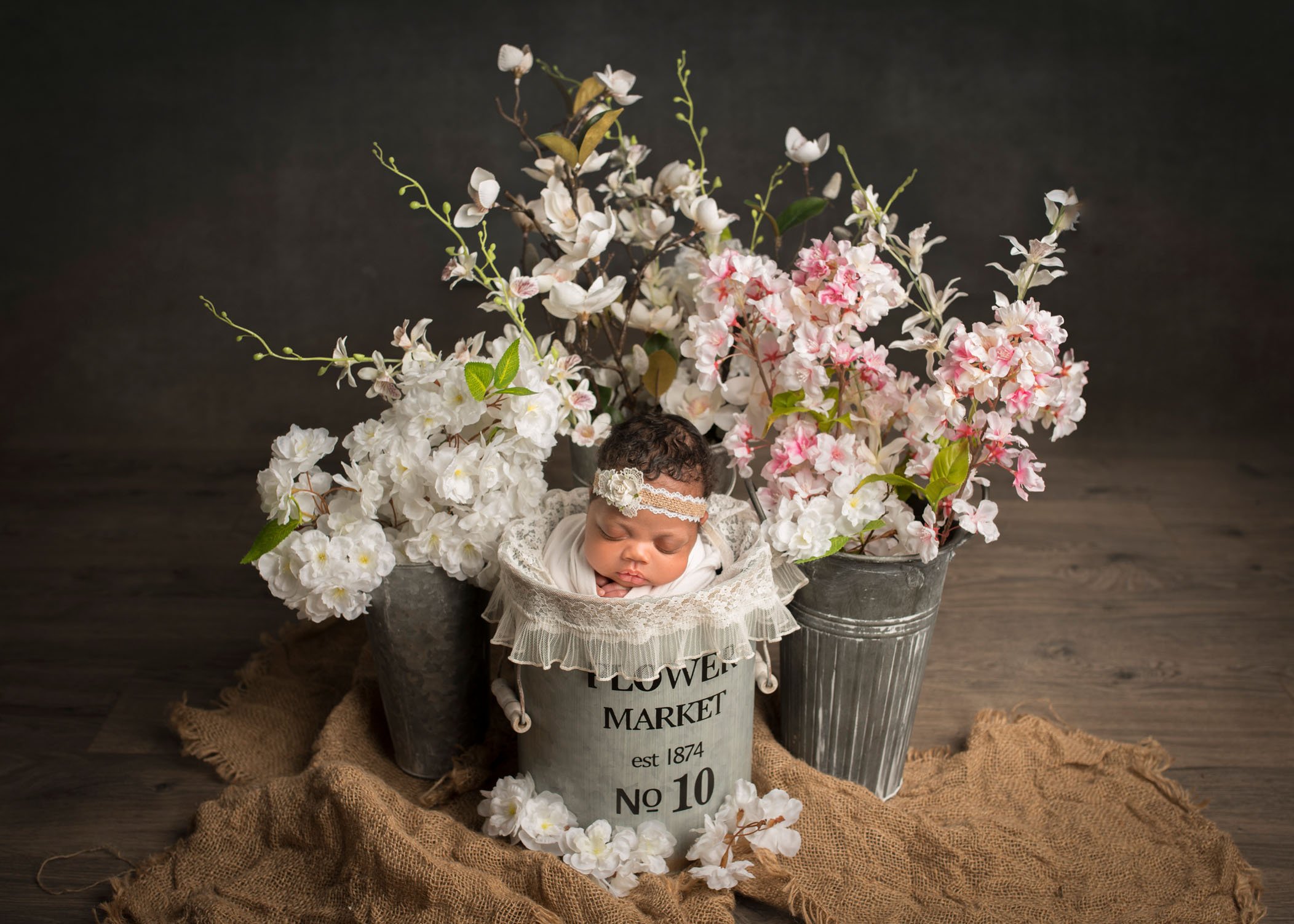african-american newborn baby girl sleeping in a flower market bucket surrounded by spring flowers