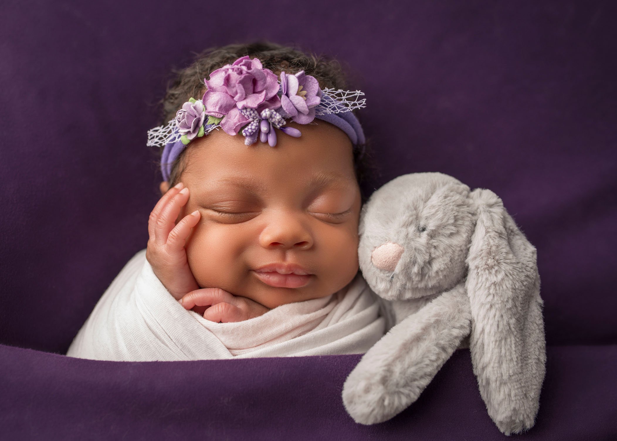 african-american newborn baby girl asleep with a stuffed bunny cuddling her