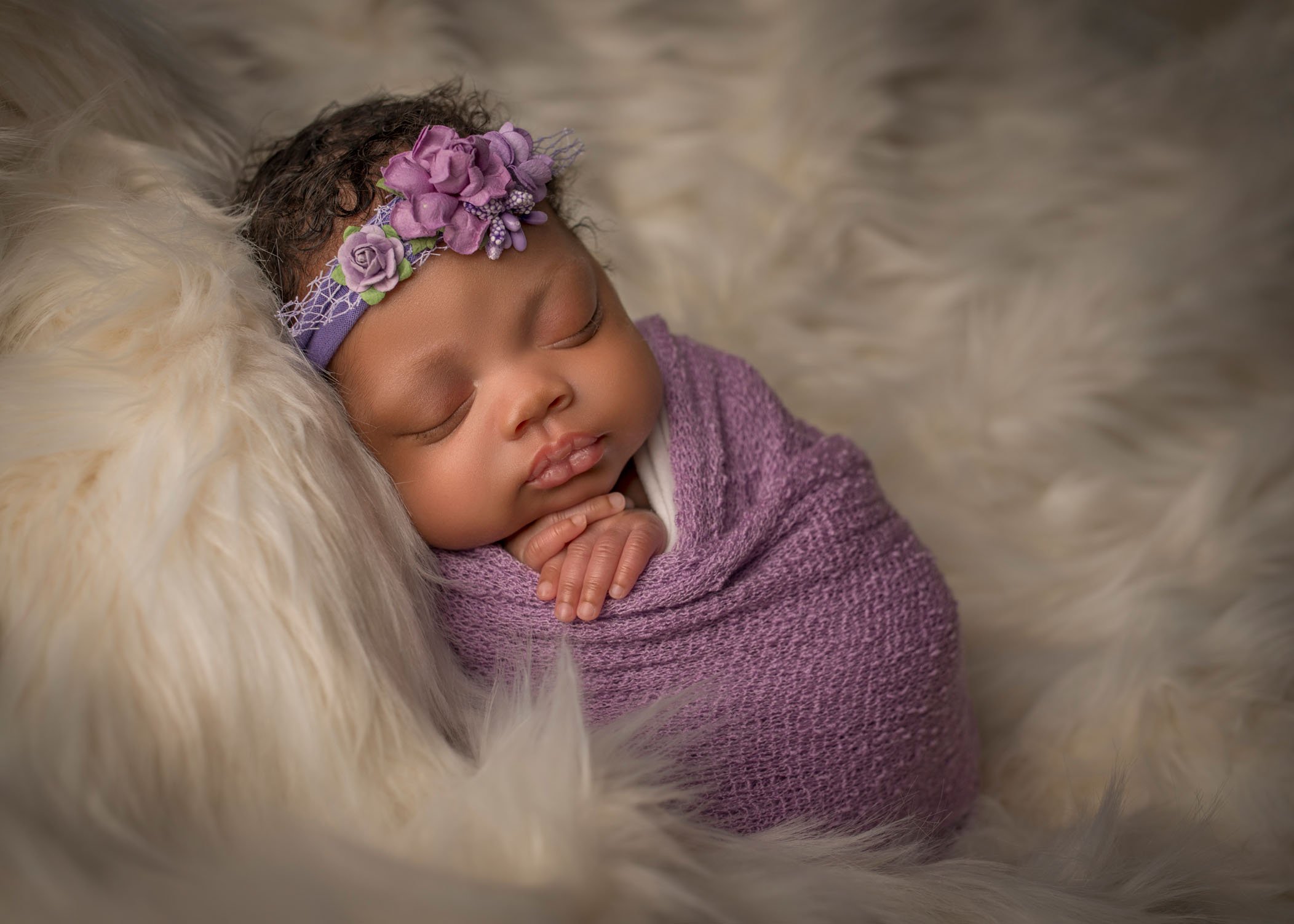 african-american newborn baby girl wrapped in lavender blanket with floral headband