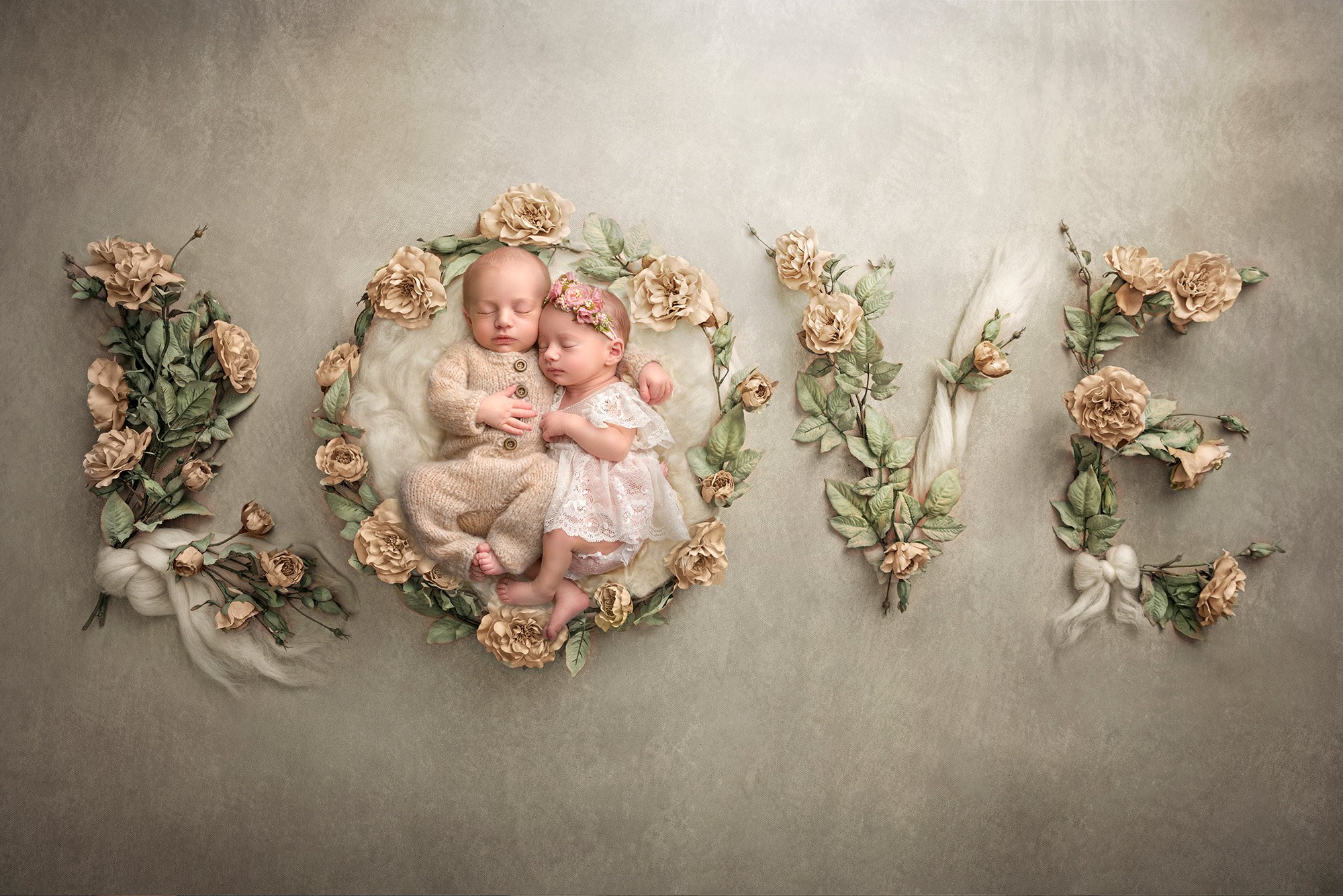 Twins newborn photography sweet newborn twins asleep on a grey background spelling out the word LOVE in flowers and bows