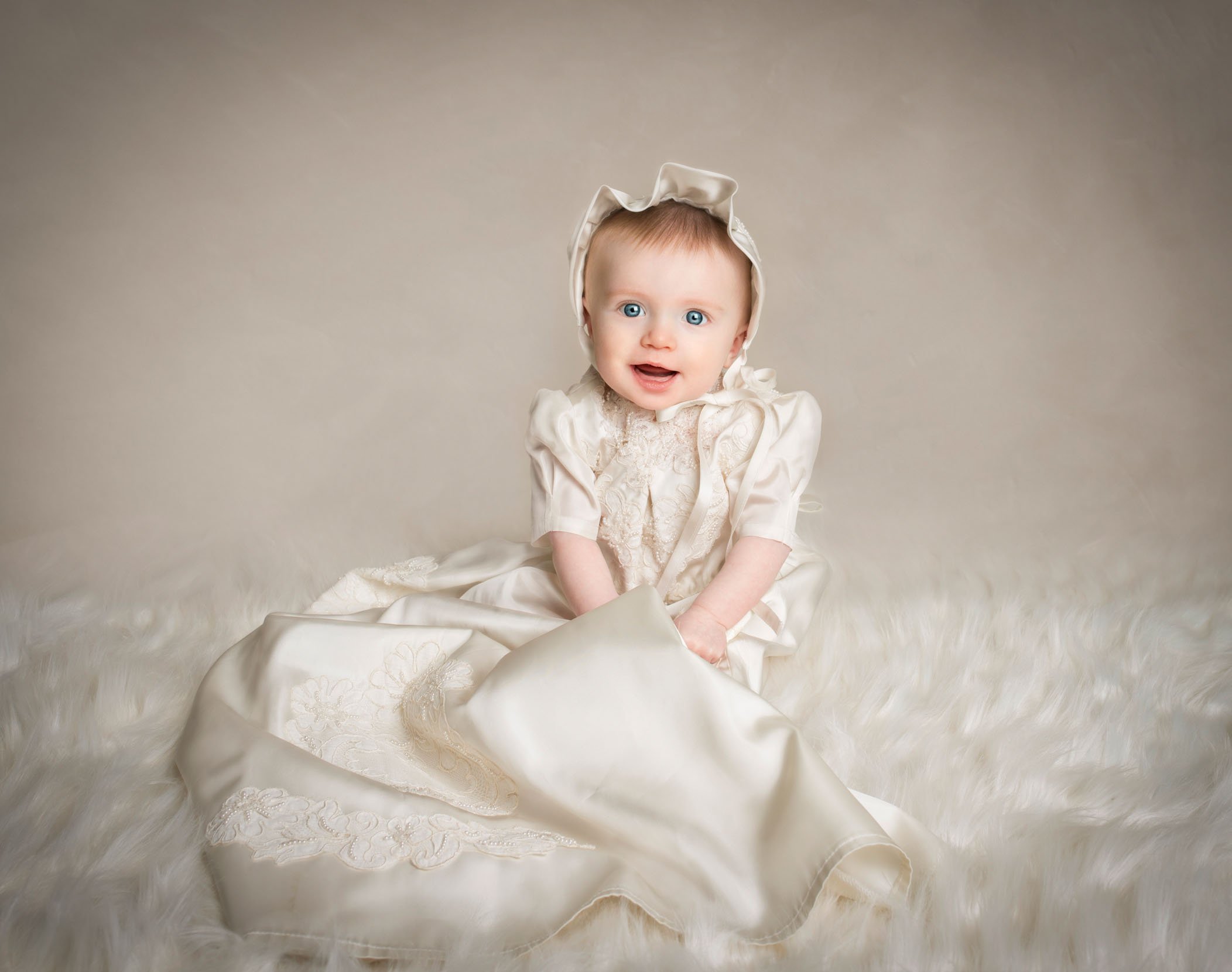 6 mo old baby girl dressed in a bonnet and fancy Christening gown