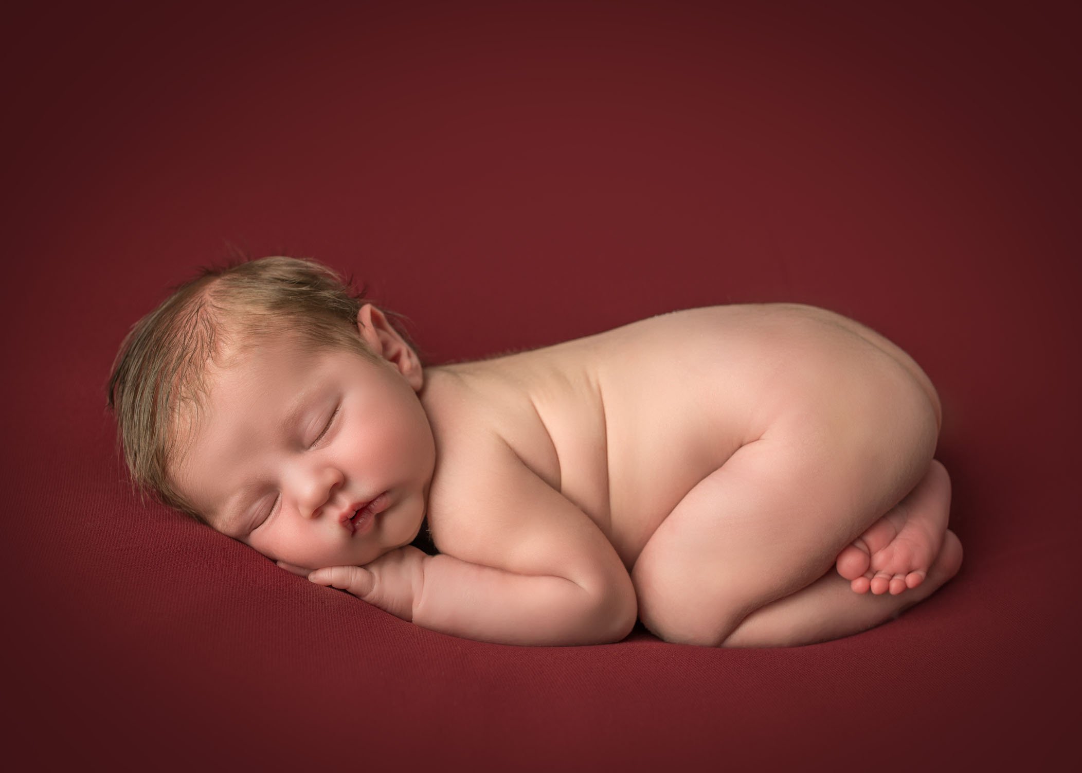 Connecticut Newborn Photographer baby sleeping on red background in bum up pose