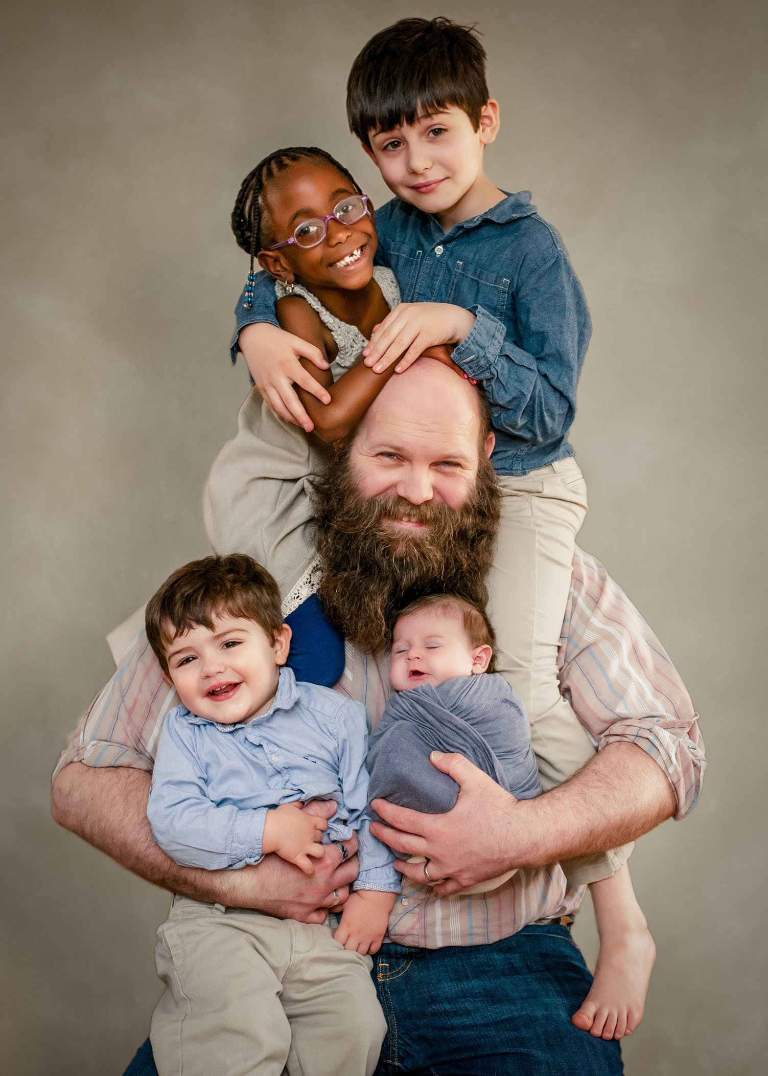 Daddy tree or kids draped all over their Dad while holding a newborn baby
