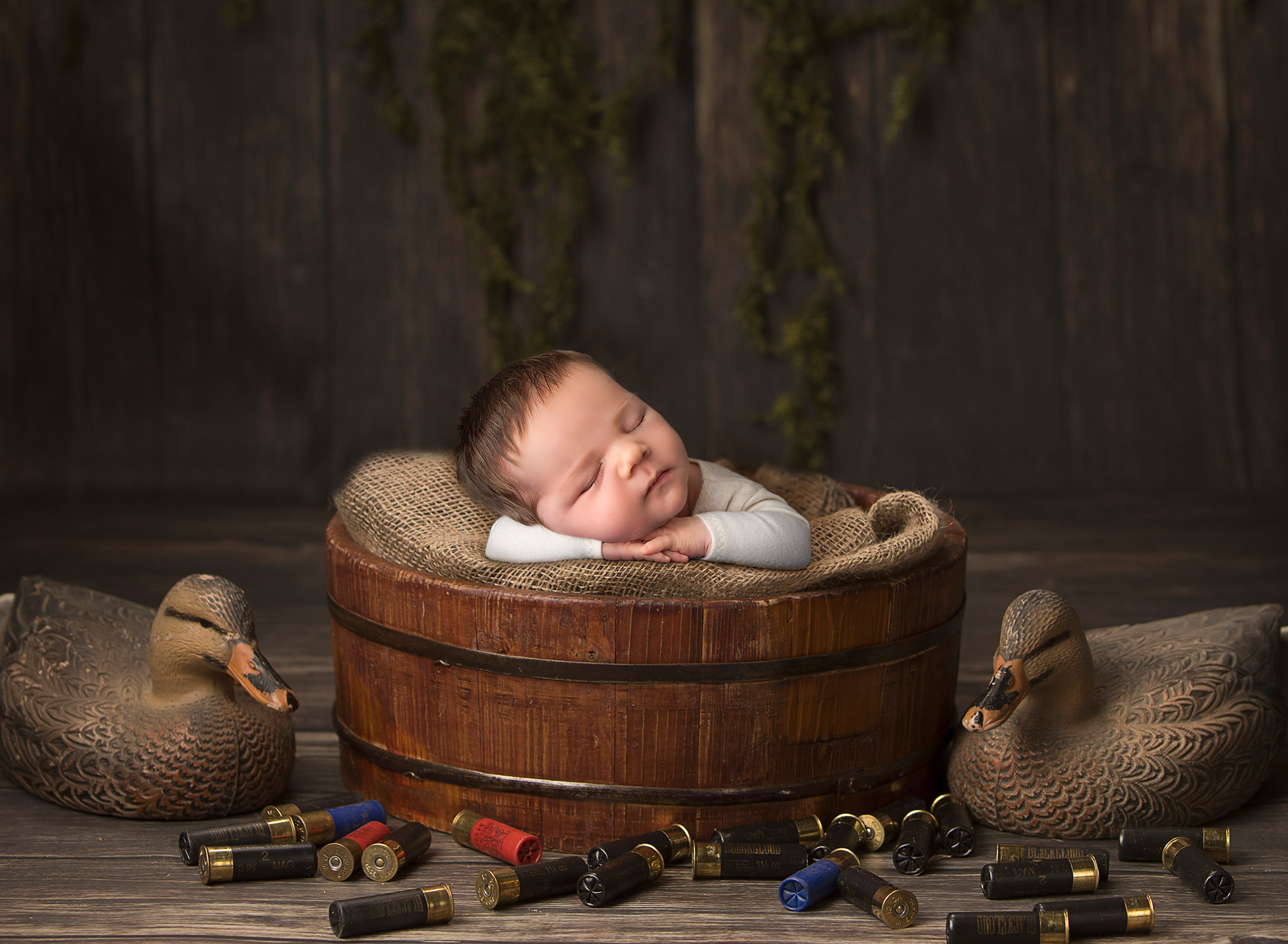 Nature Lover Newborn Photos newborn baby boy sleeping in a bucket surrounded by duck hunting gear
