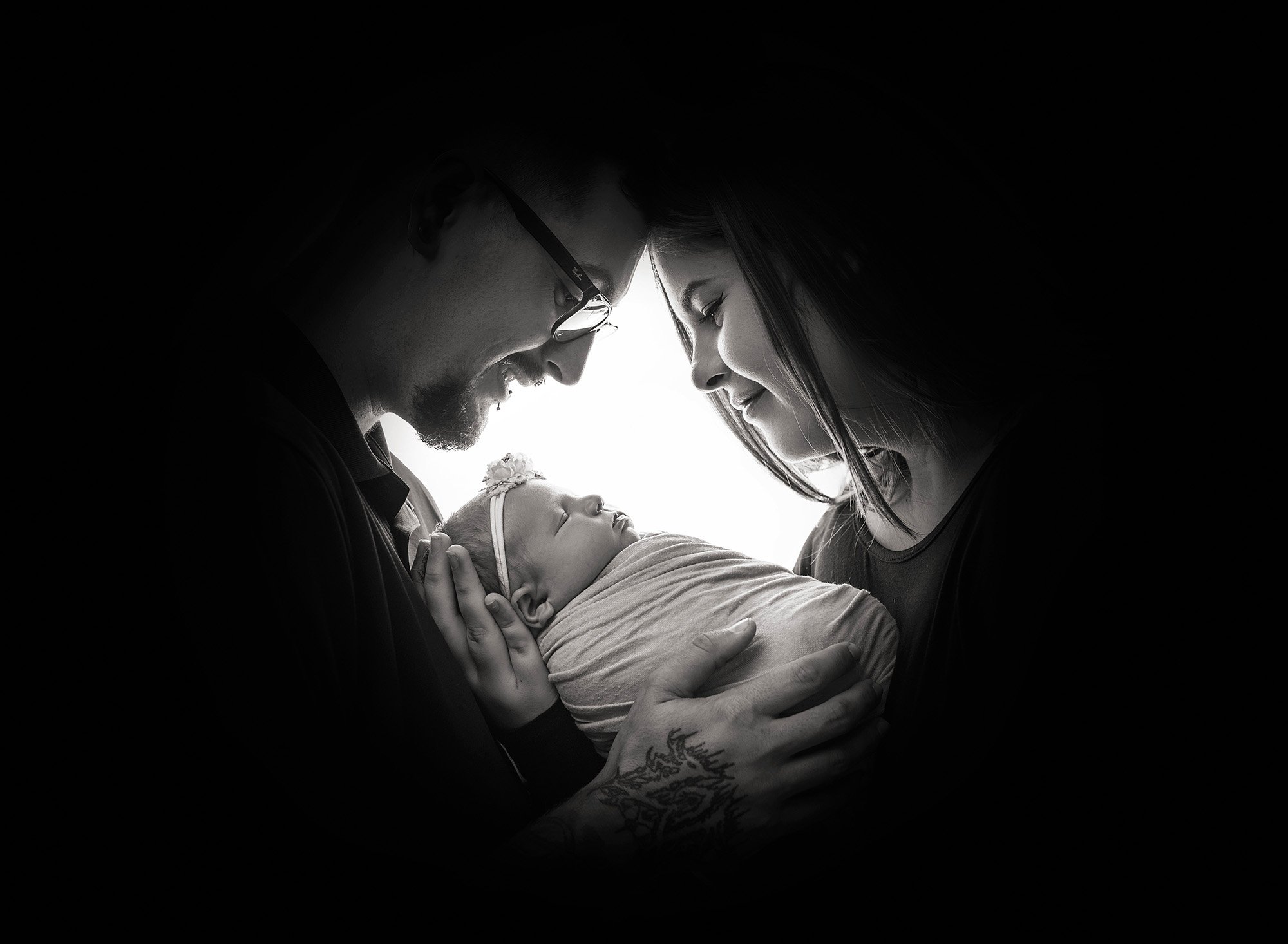 silhouette shadow of new parents face's while cradling their newborn baby girl