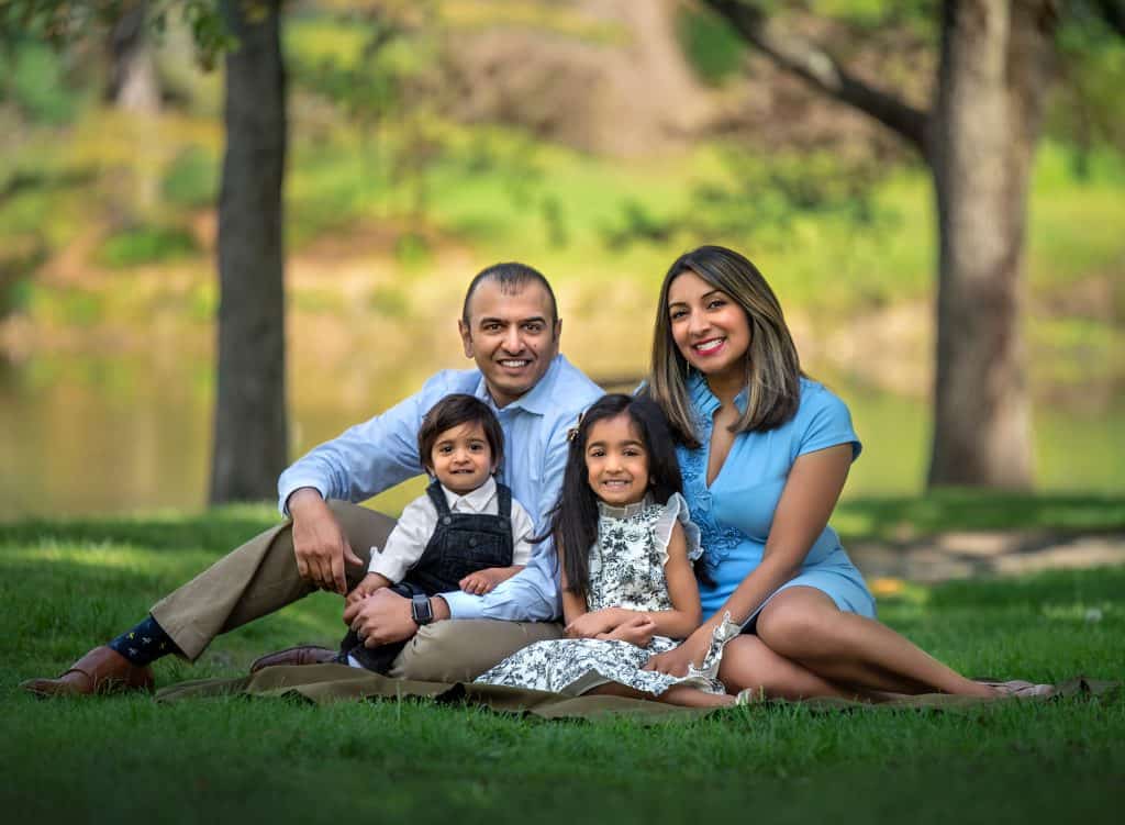 couple smiling sitting outside with daughter and son with trees in the background