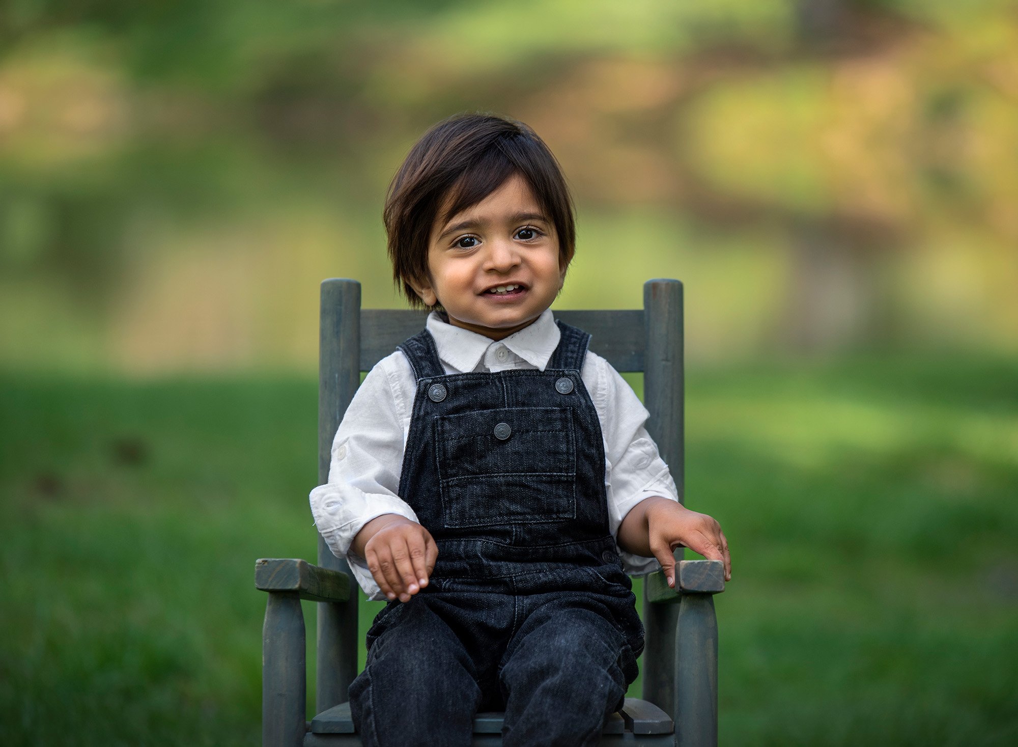 First Birthday Session little boy dressed in overalls sitting on rustic chair