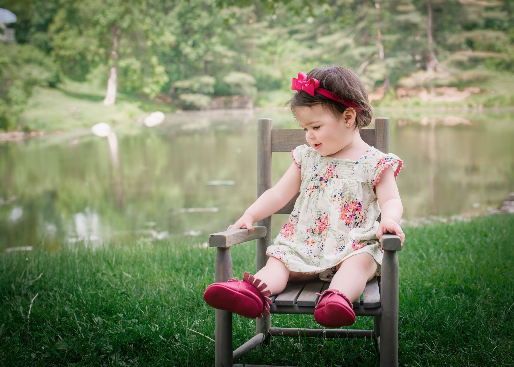 1 year old little girl sitting in a chair in the garden