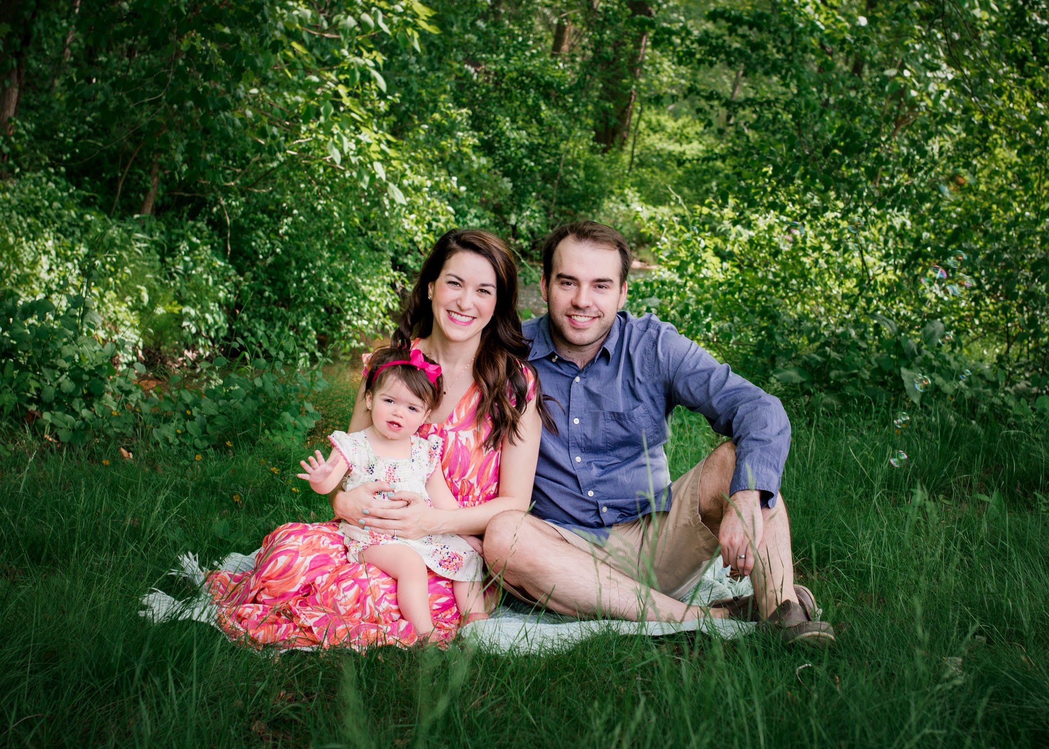 family photo of mom dad and baby girl in the garden in spring